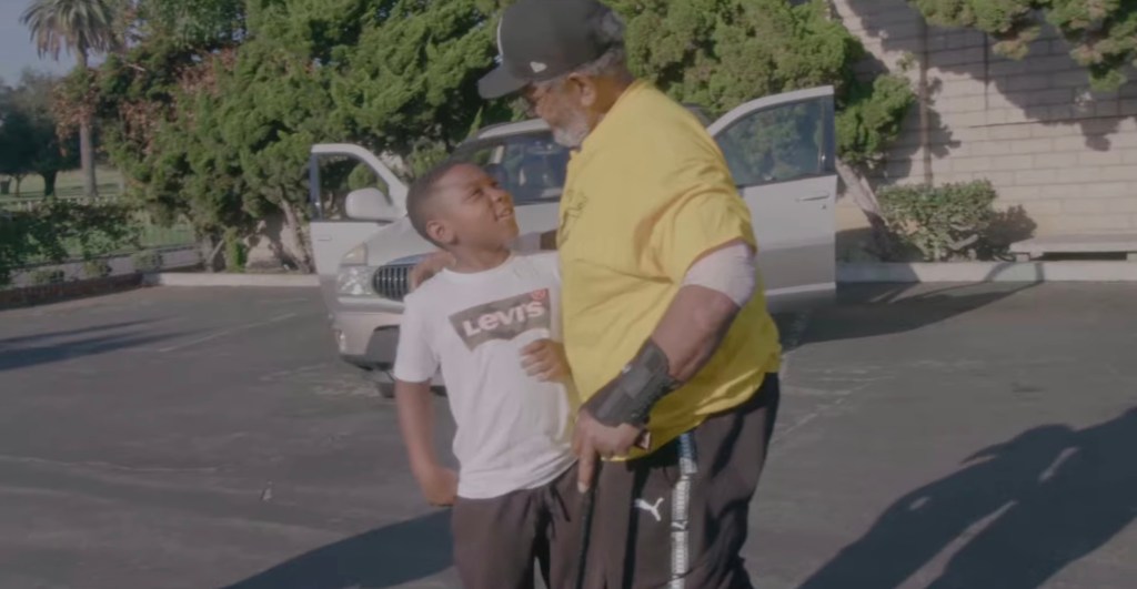 Lionel Williams and a young boy conversing in a parking lot.
