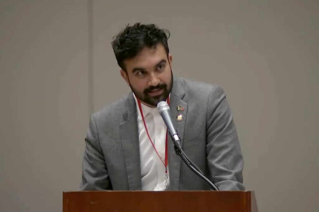 Assemblymember Zohran Mamdani speaking at a podium.