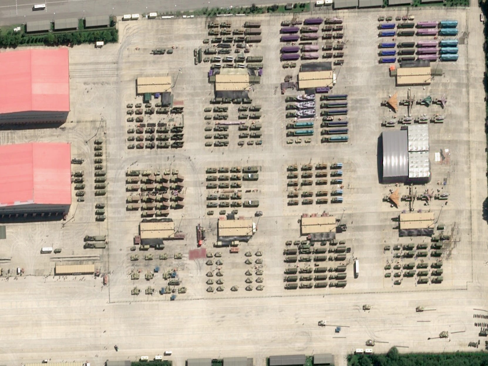 A satellite image of the staging area shows over 100 mobile systems, vehicles, and drones from above.