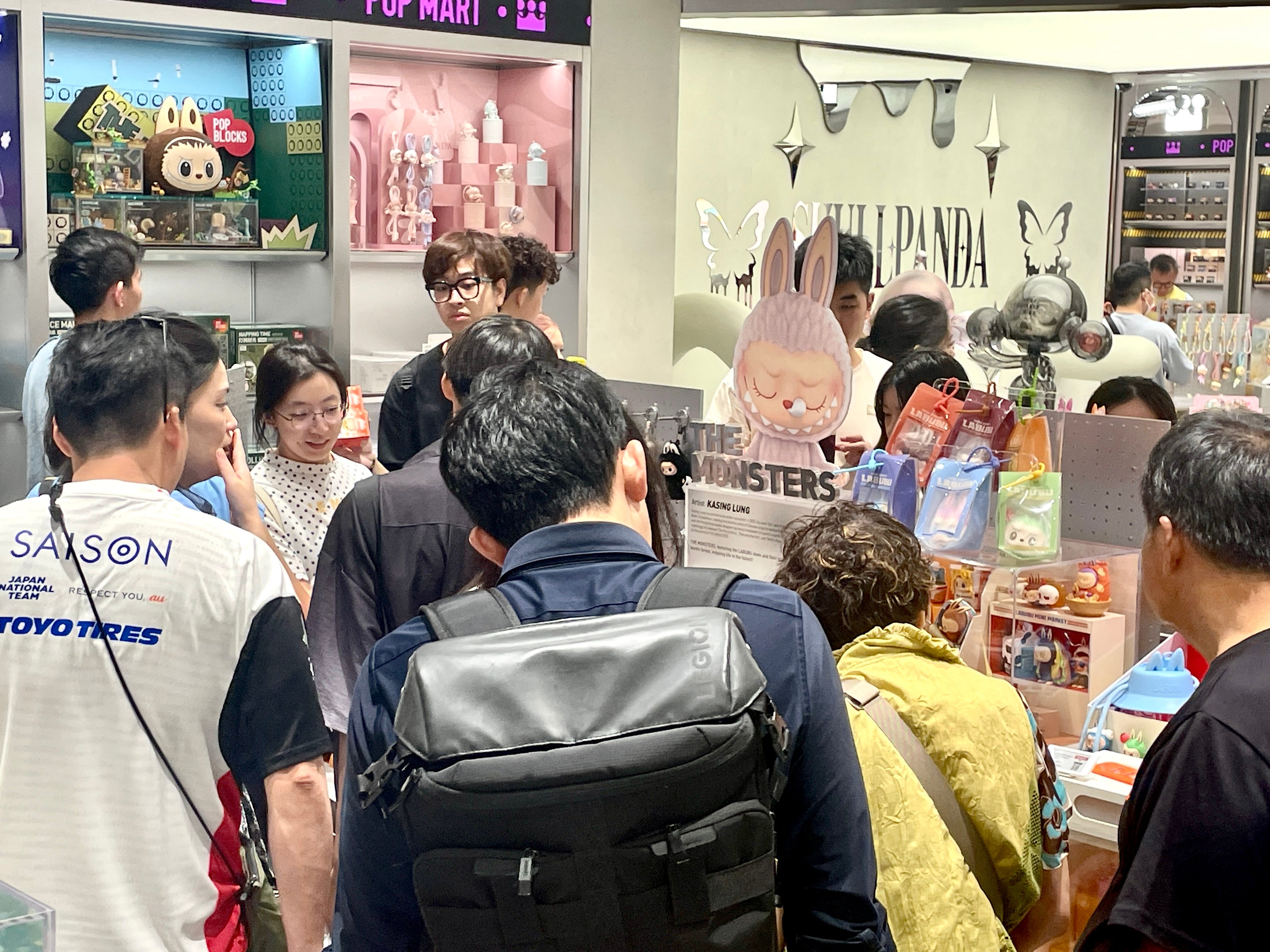 Customers crowded around "The Monsters" island in a Pop Mart store in Singapore, looking at the mini Labubus on display.