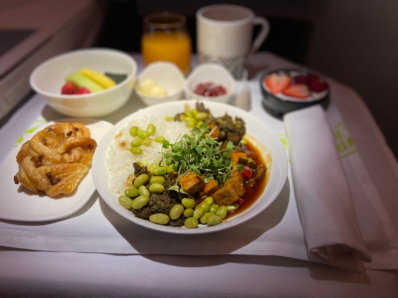 Meal on airplane tray table with linen napkin and tablecloth