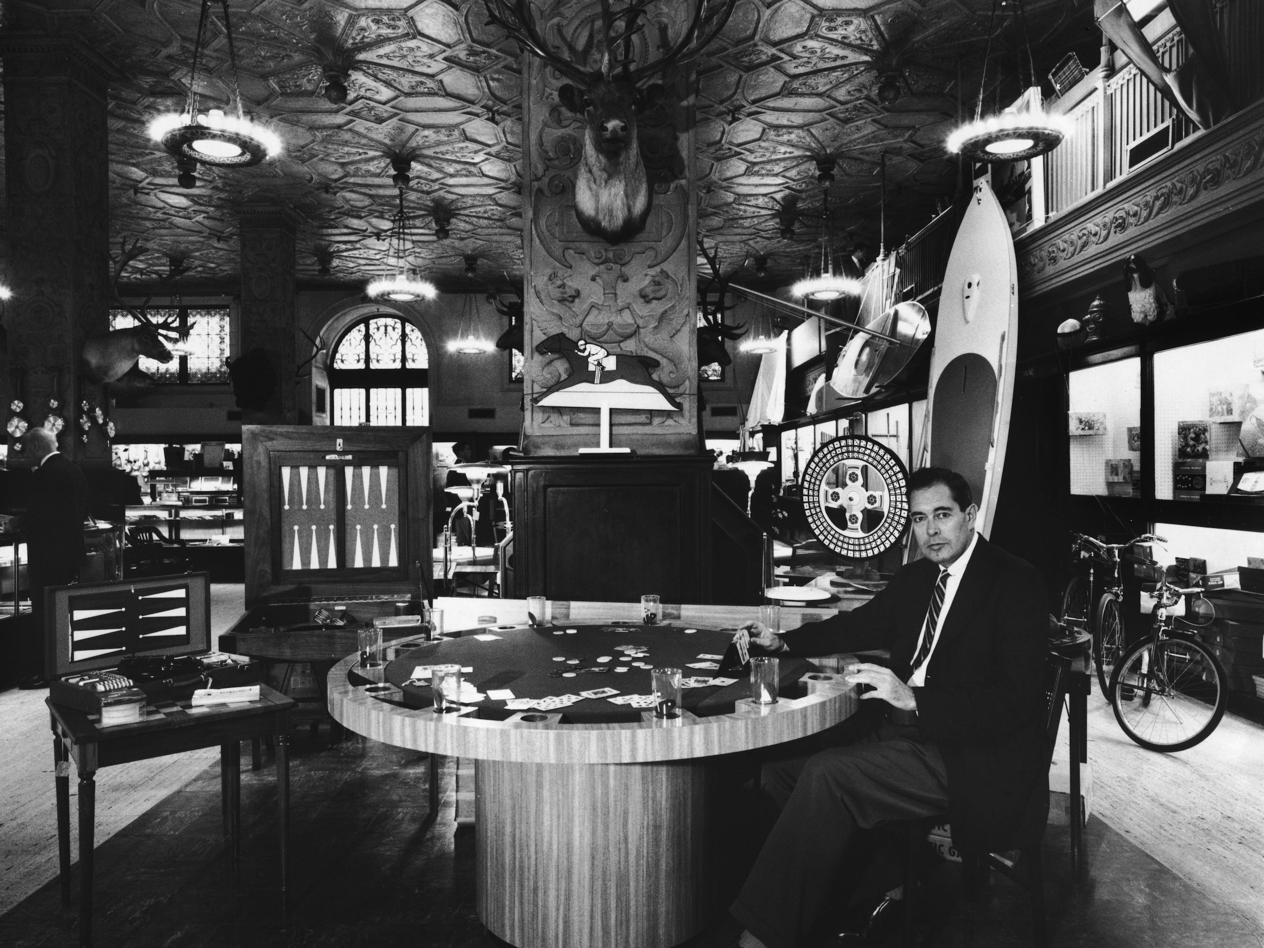Man sits at table inside Abercrombie & Fitch store with animal heads, sports equipment around him