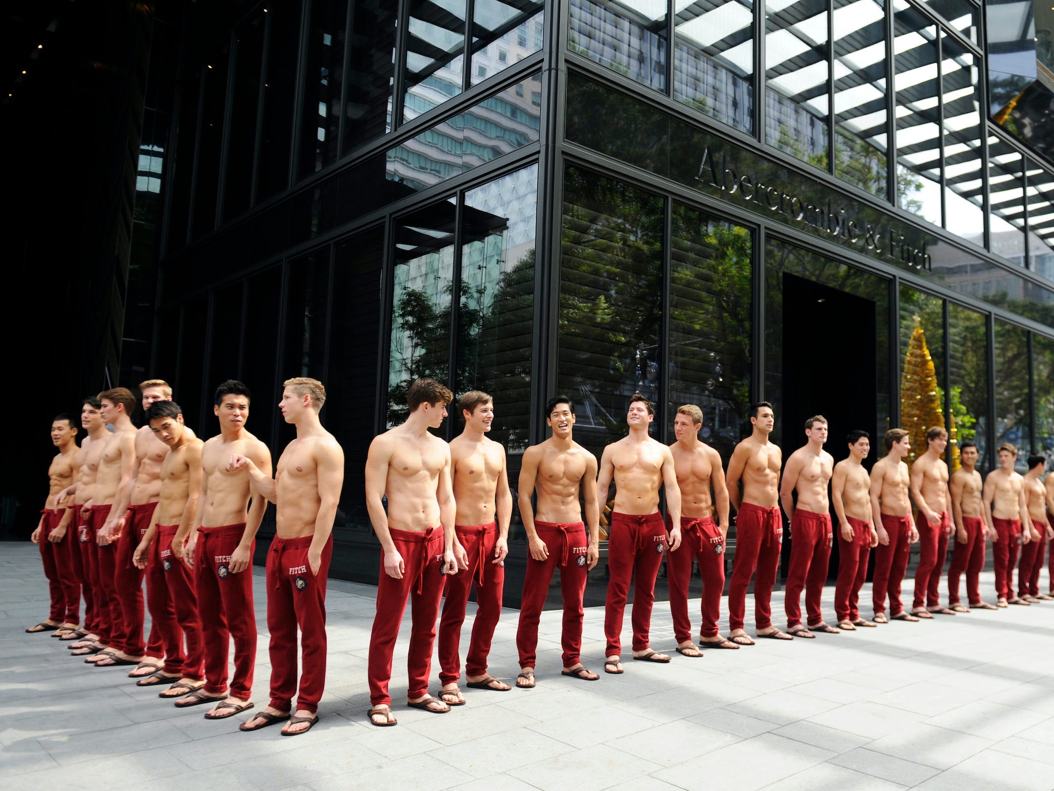 Abercrombie & Fitch shirtless male models pose in a line outside a store in Singapore