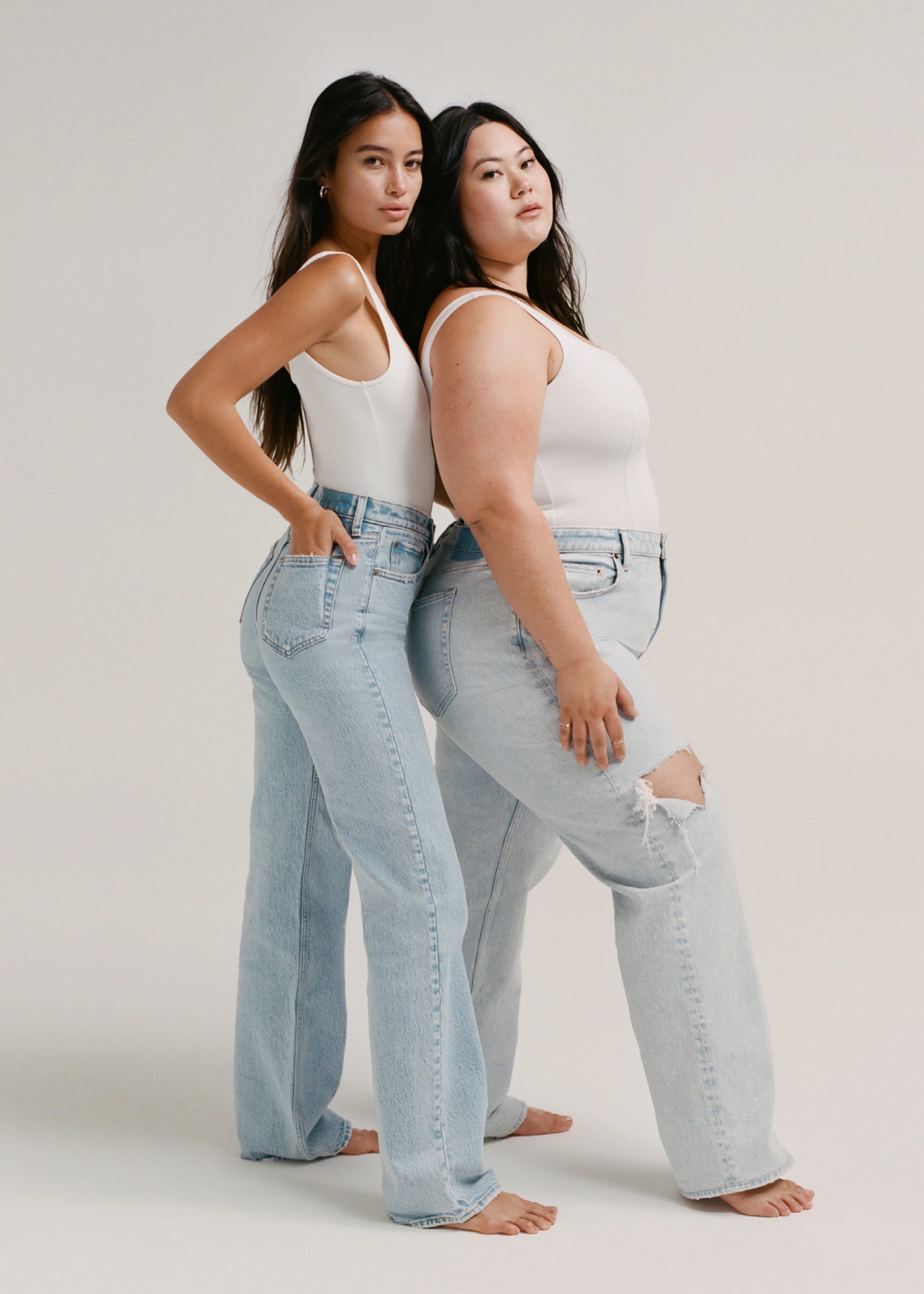 Two women Abercrombie models in jeans and white tank tops pose back to front