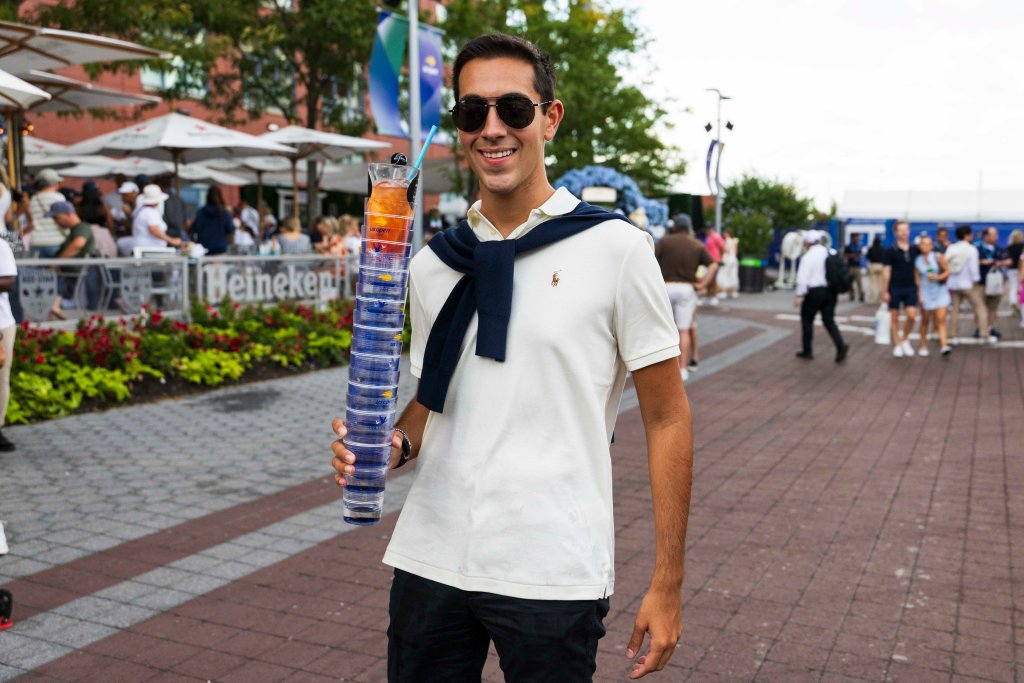 Man holding a large stack of US Open drinks at the tennis center.