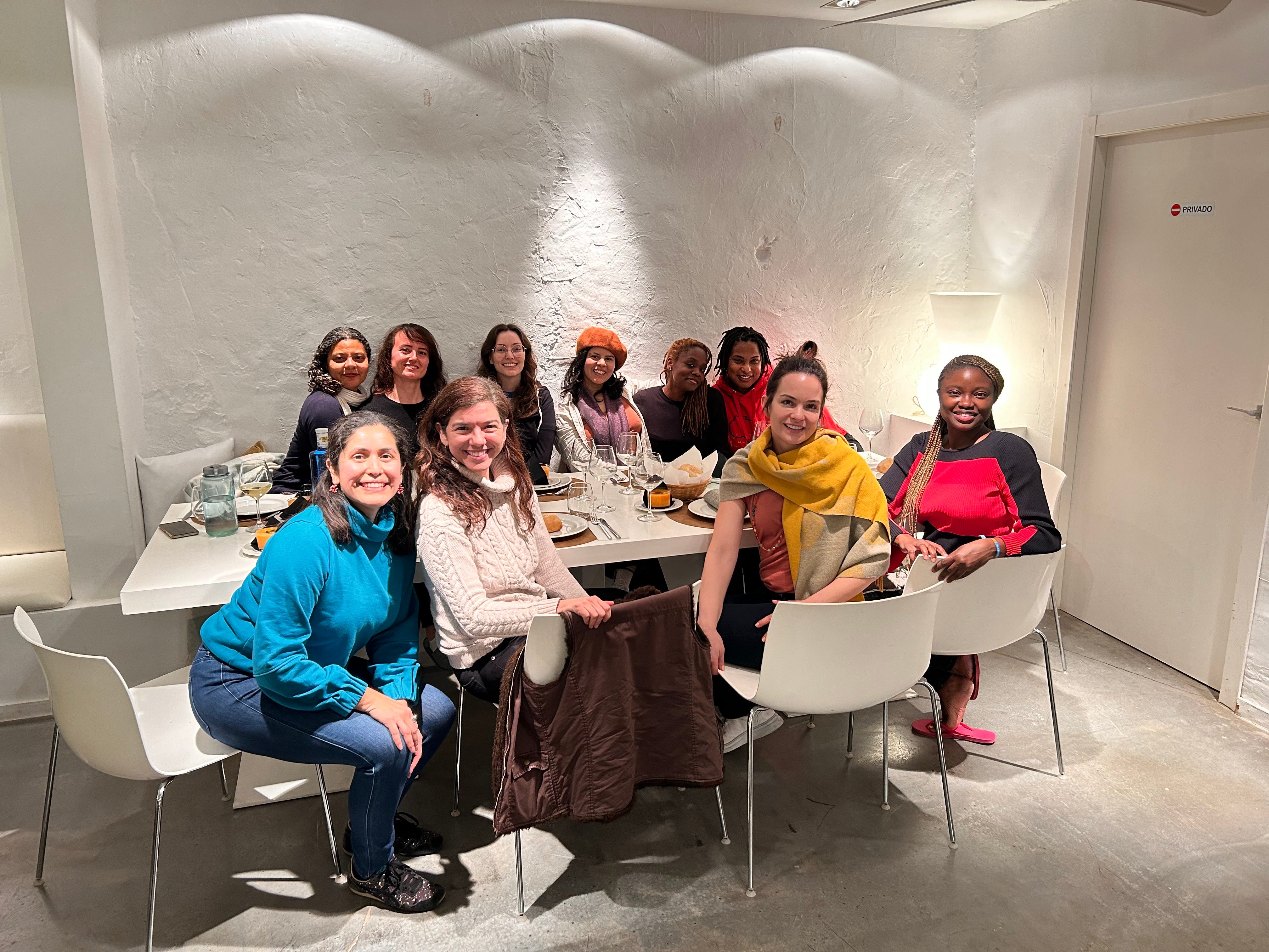 Christine Job (5th person in back row of chairs) and friends at a dinner table.