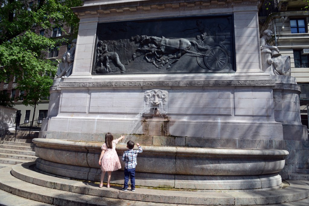 Firemen's memorial fountain with children playing in front.