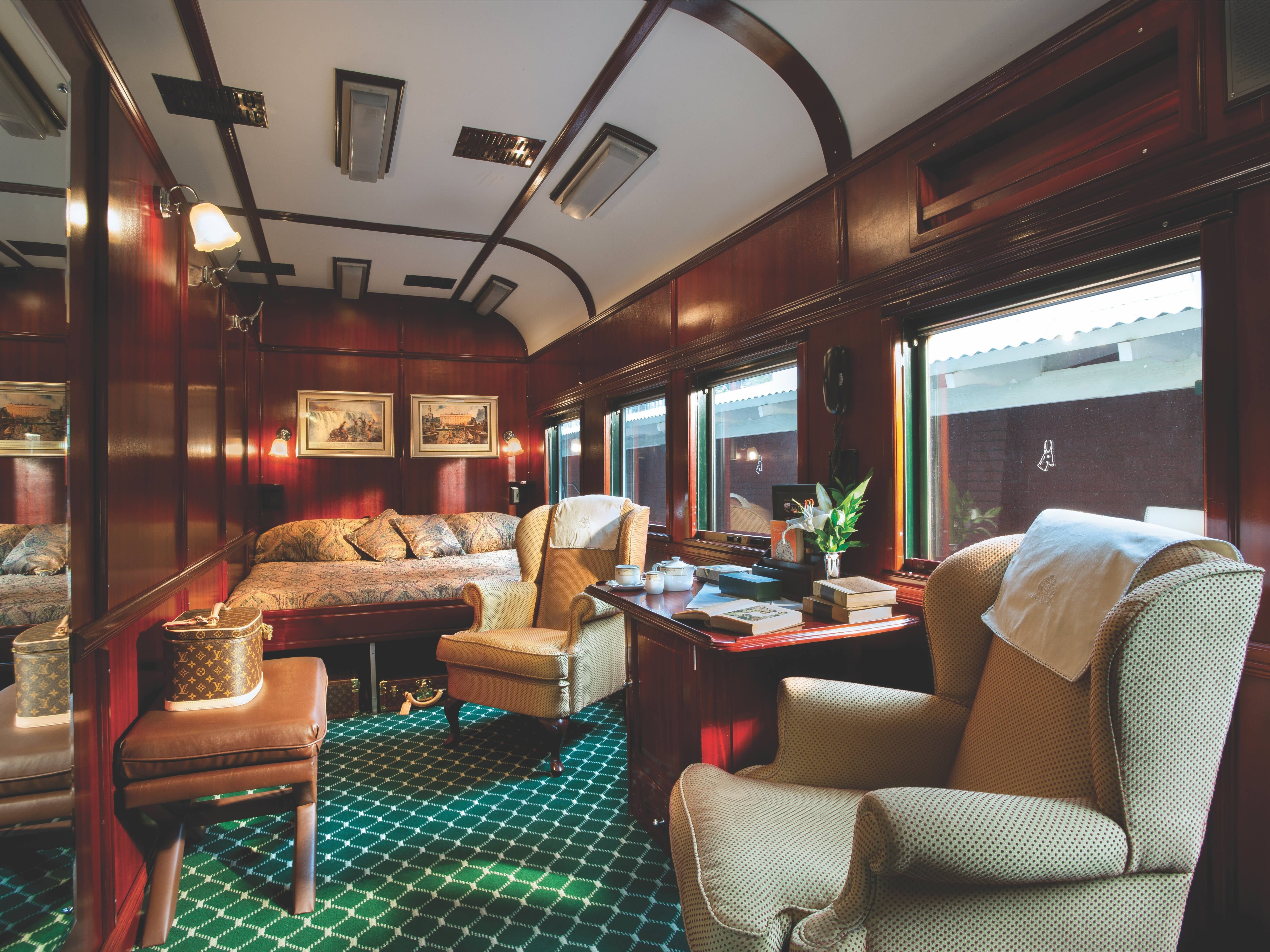 A train cabin with sofa, bed, mirror, and large windows.
