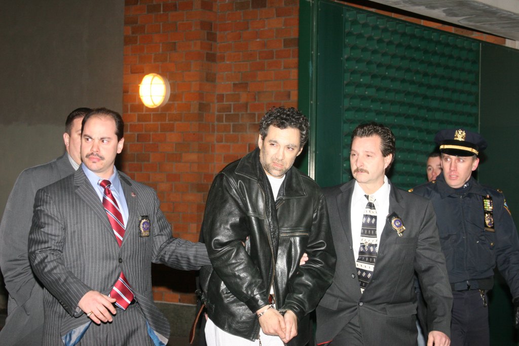 Peter Braunstein in handcuffs, escorted by police officers.