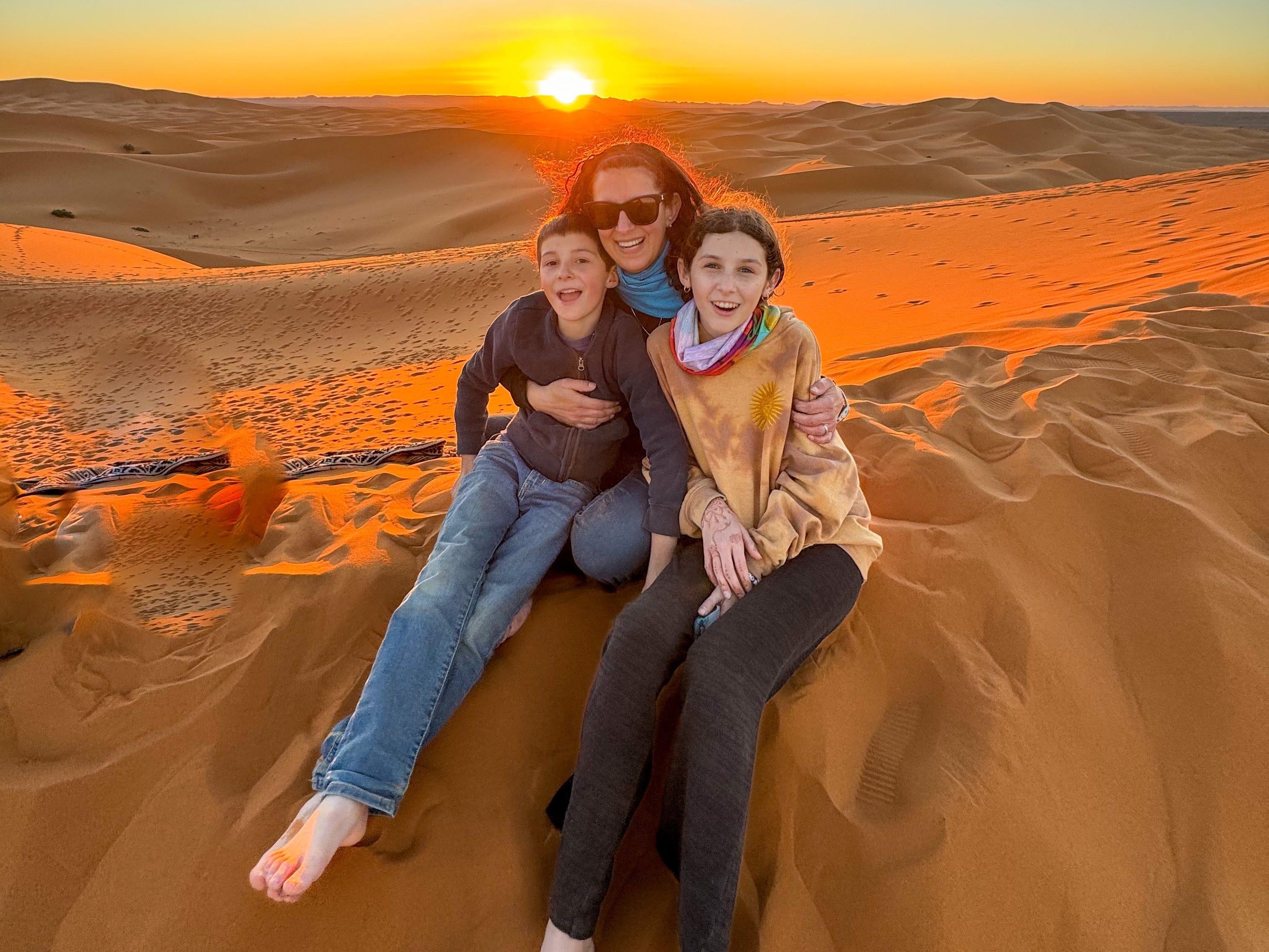 Jamie poses with her kids in the desert at sunset.
