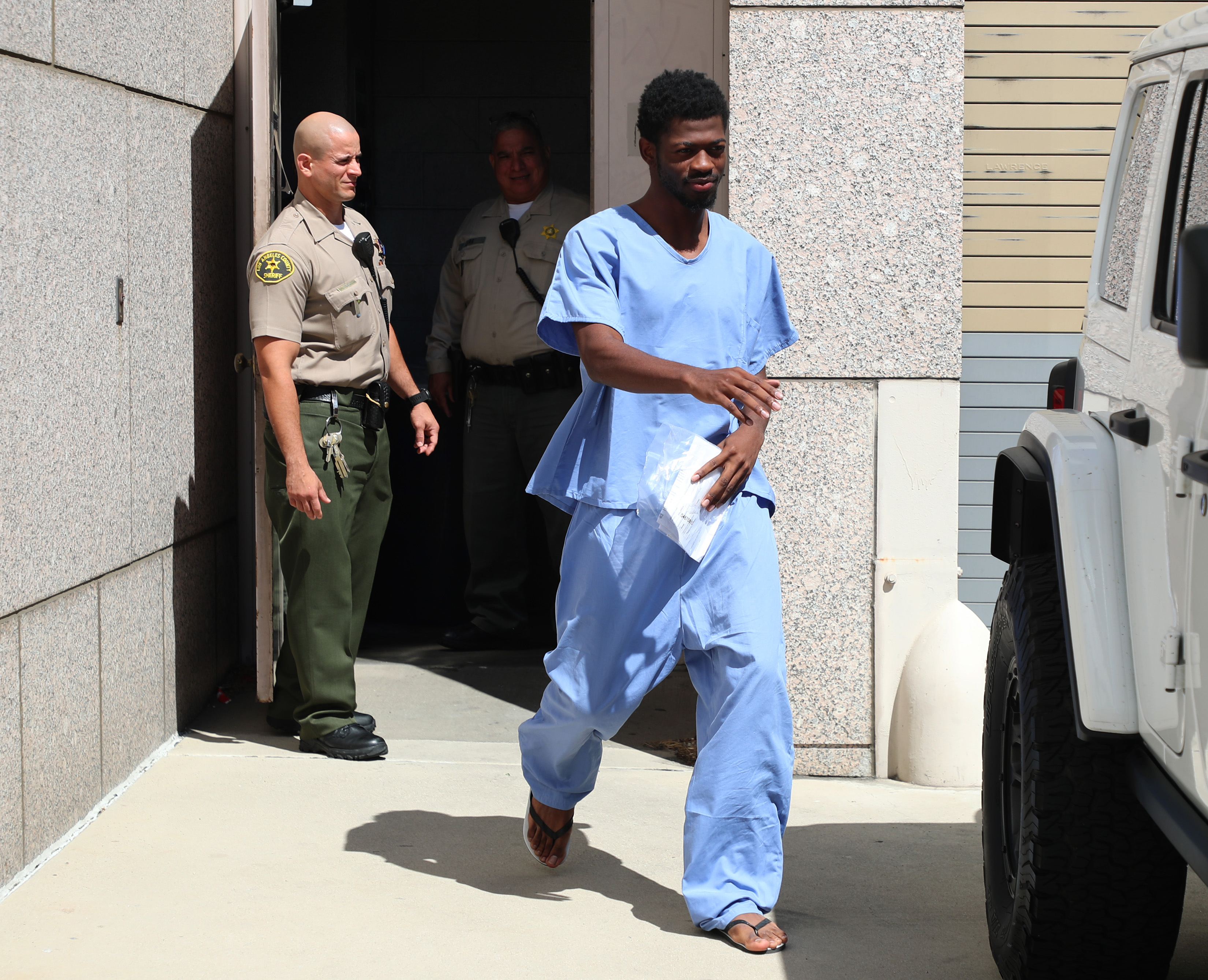 Lil Nas X outside a jail in blue. 