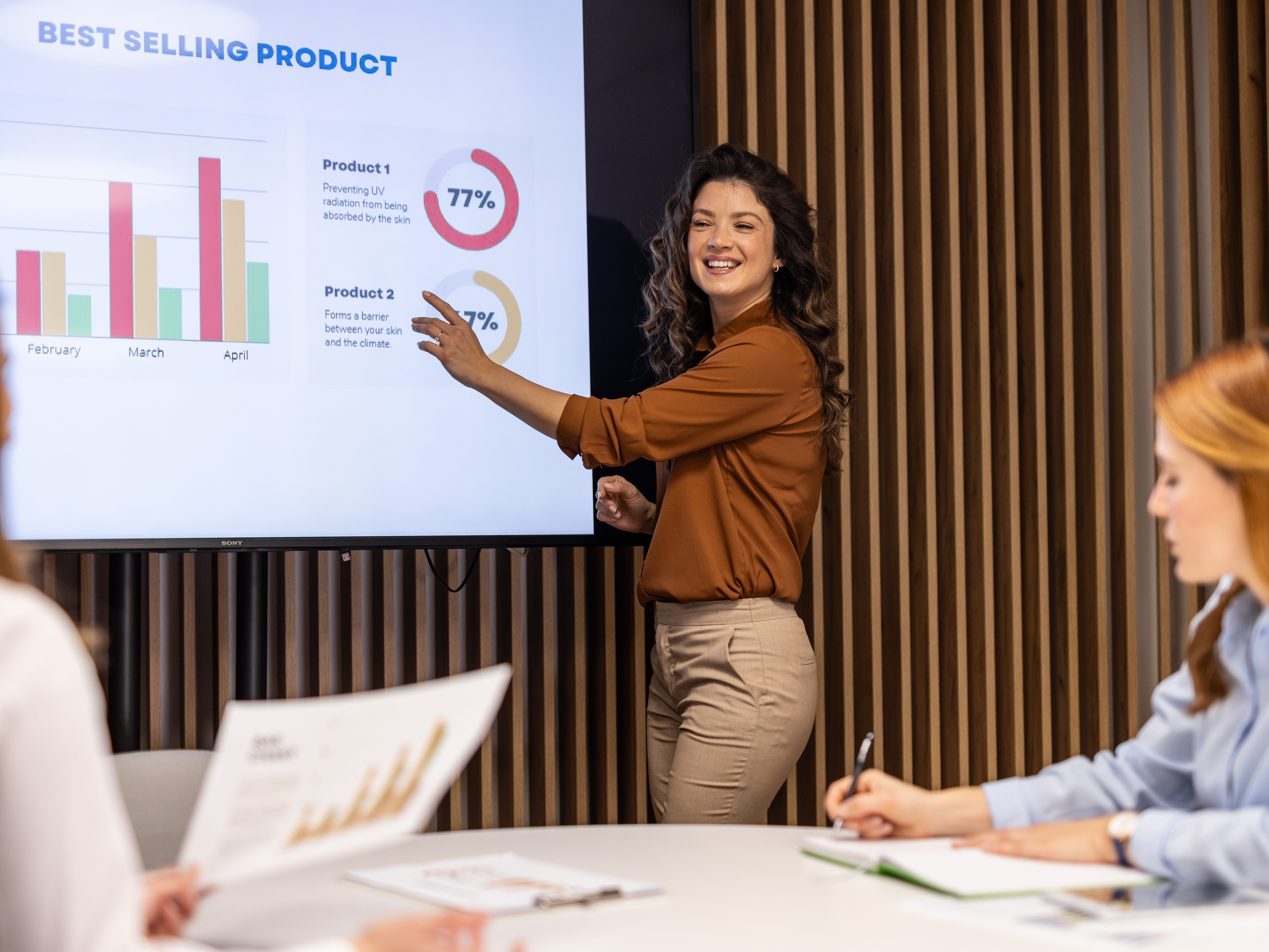 Person pointing at a monitor with some data graphics about products