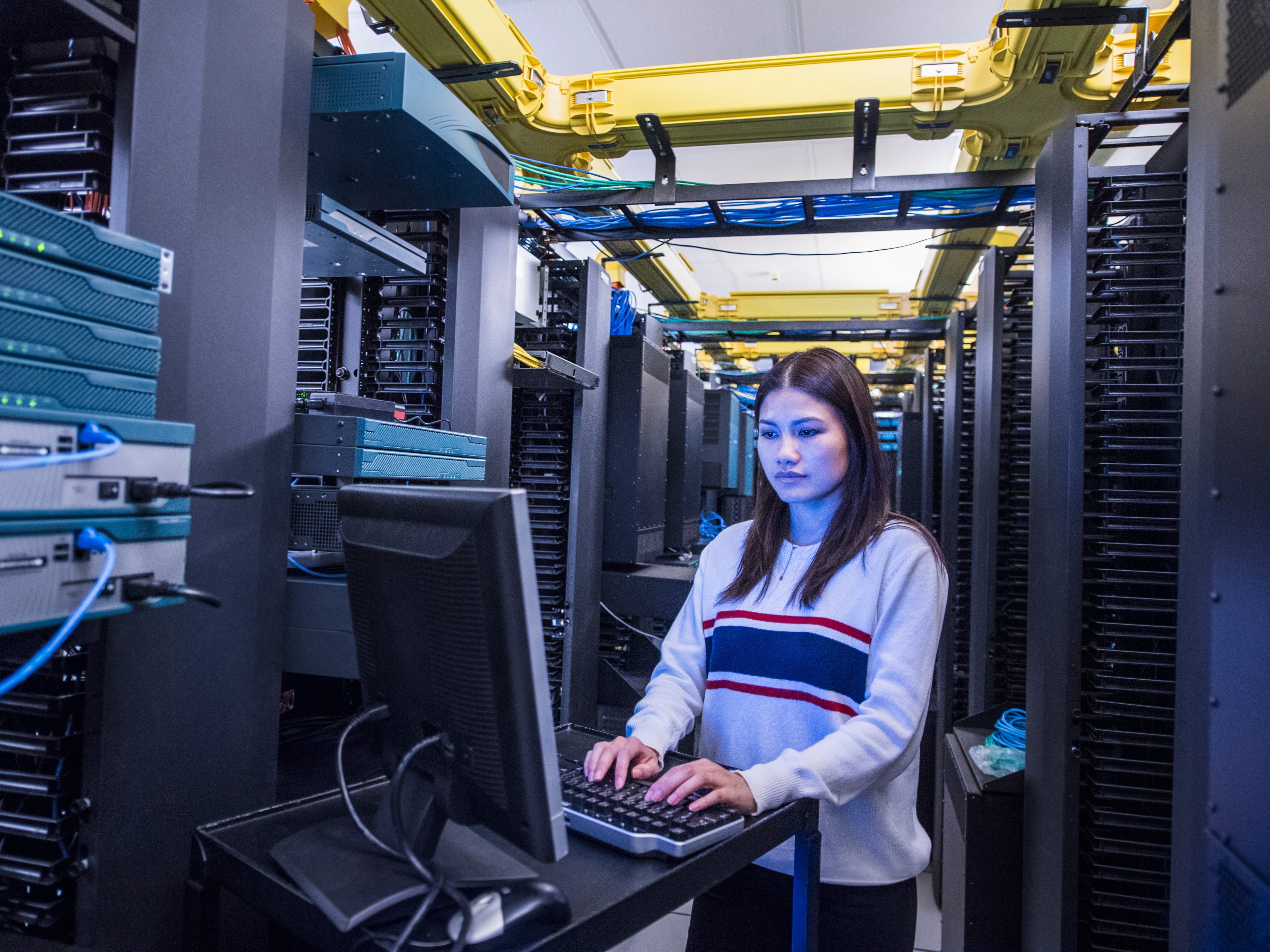 Person typing on a computer keyboard in a server room