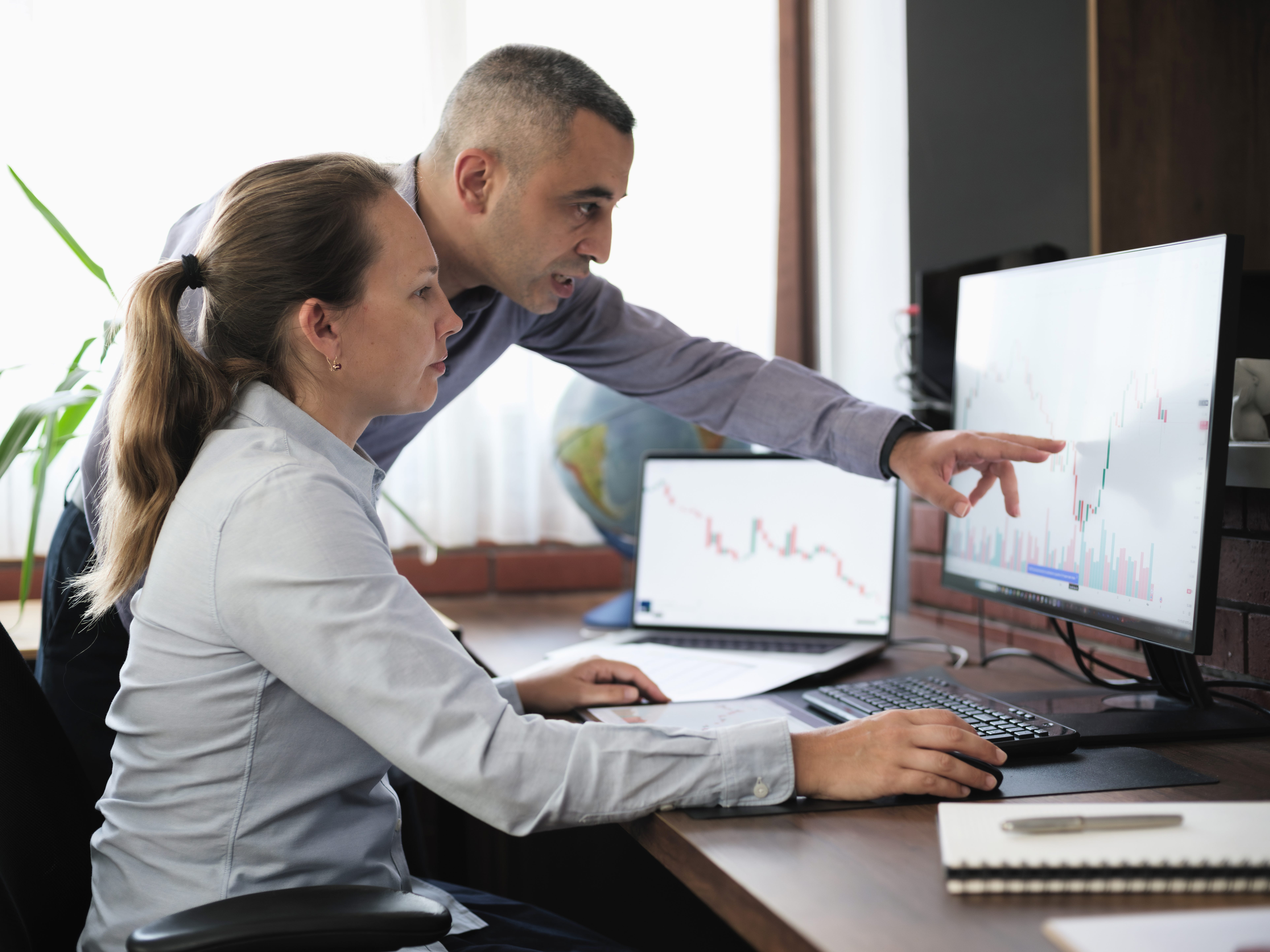 Two people looking at data on a computer screen in an office