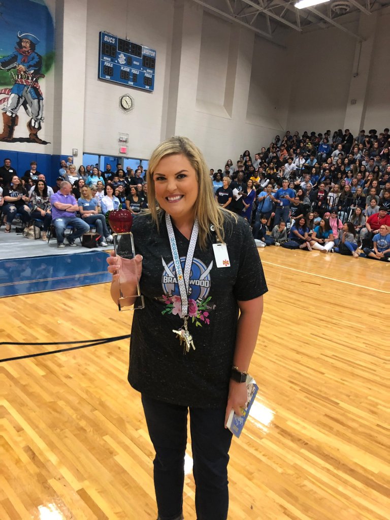 Brandyn Hargrove, Brazoswood High School teacher, holding an award in a gymnasium.