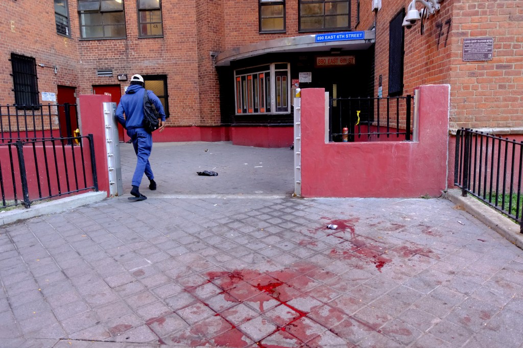 Blood stains on the sidewalk outside a building after a shooting.