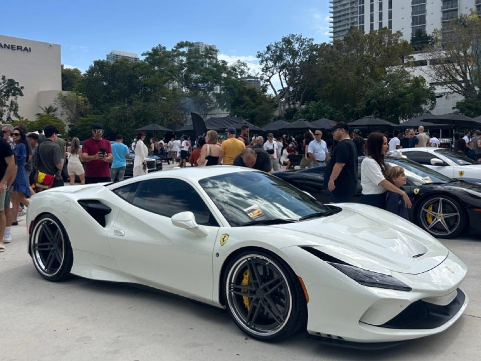 White car parked in Miami with crowds behind it