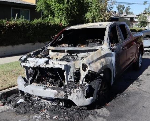 Burned-out truck on residential street.