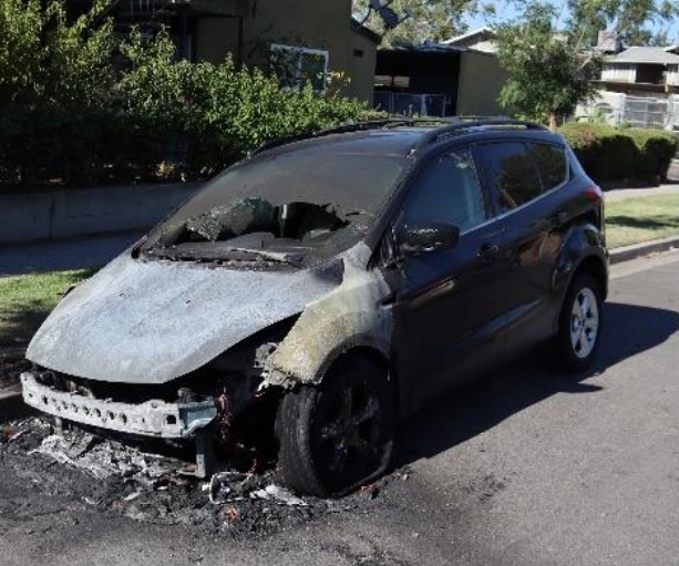 Burned-out car on a residential street.