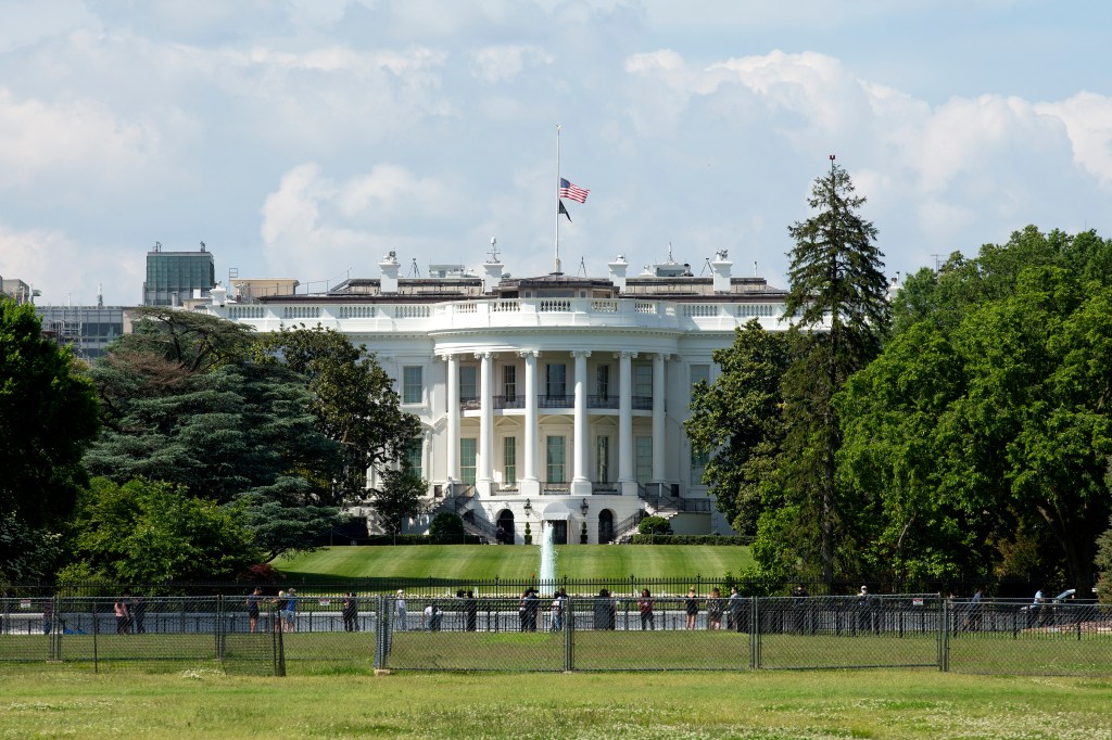 The White House with the American flag at half-staff.