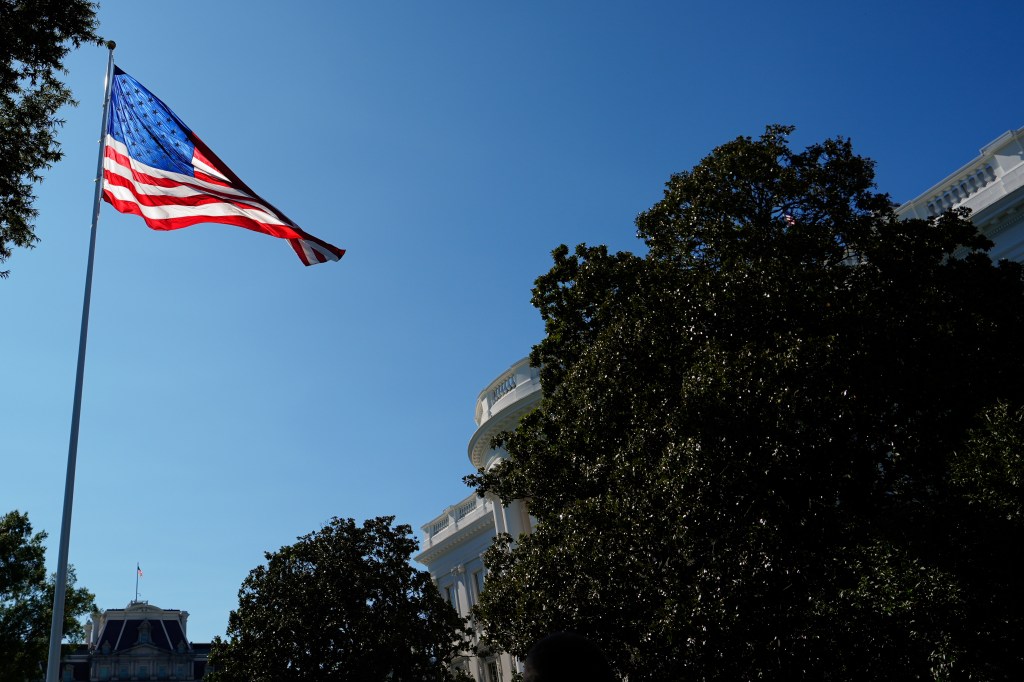 US flag flying in front of the White House.