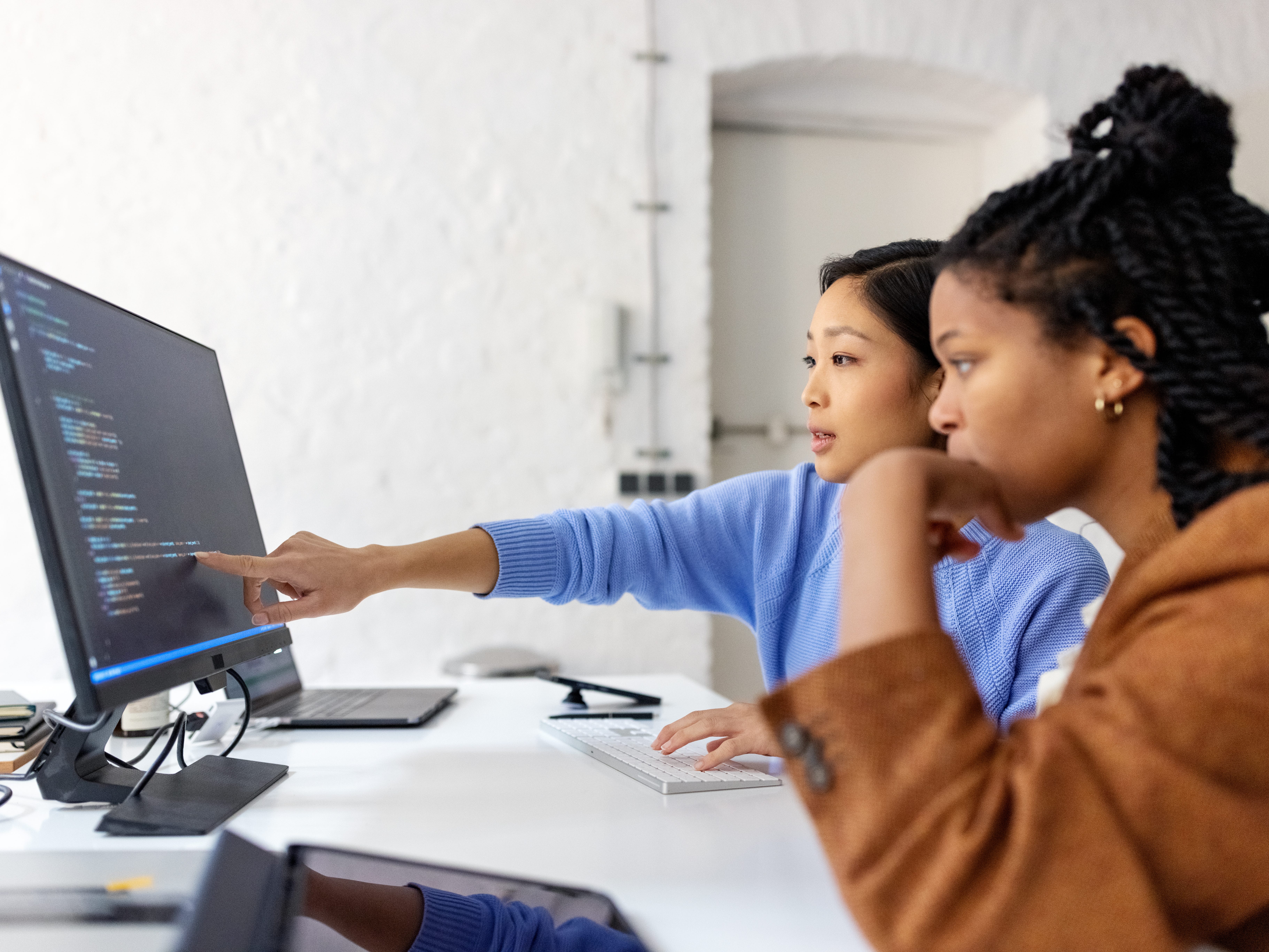Two software developers are looking at code on a computer screen
