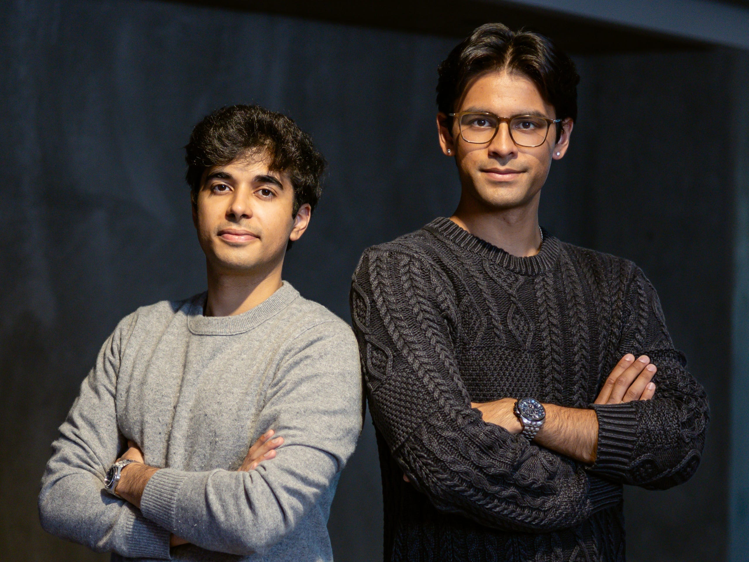 Bluejay cofounders Rohan Vasishth and Faraz Siddiqi, with their arms crossed and standing shoulder to shoulder in grey sweaters.