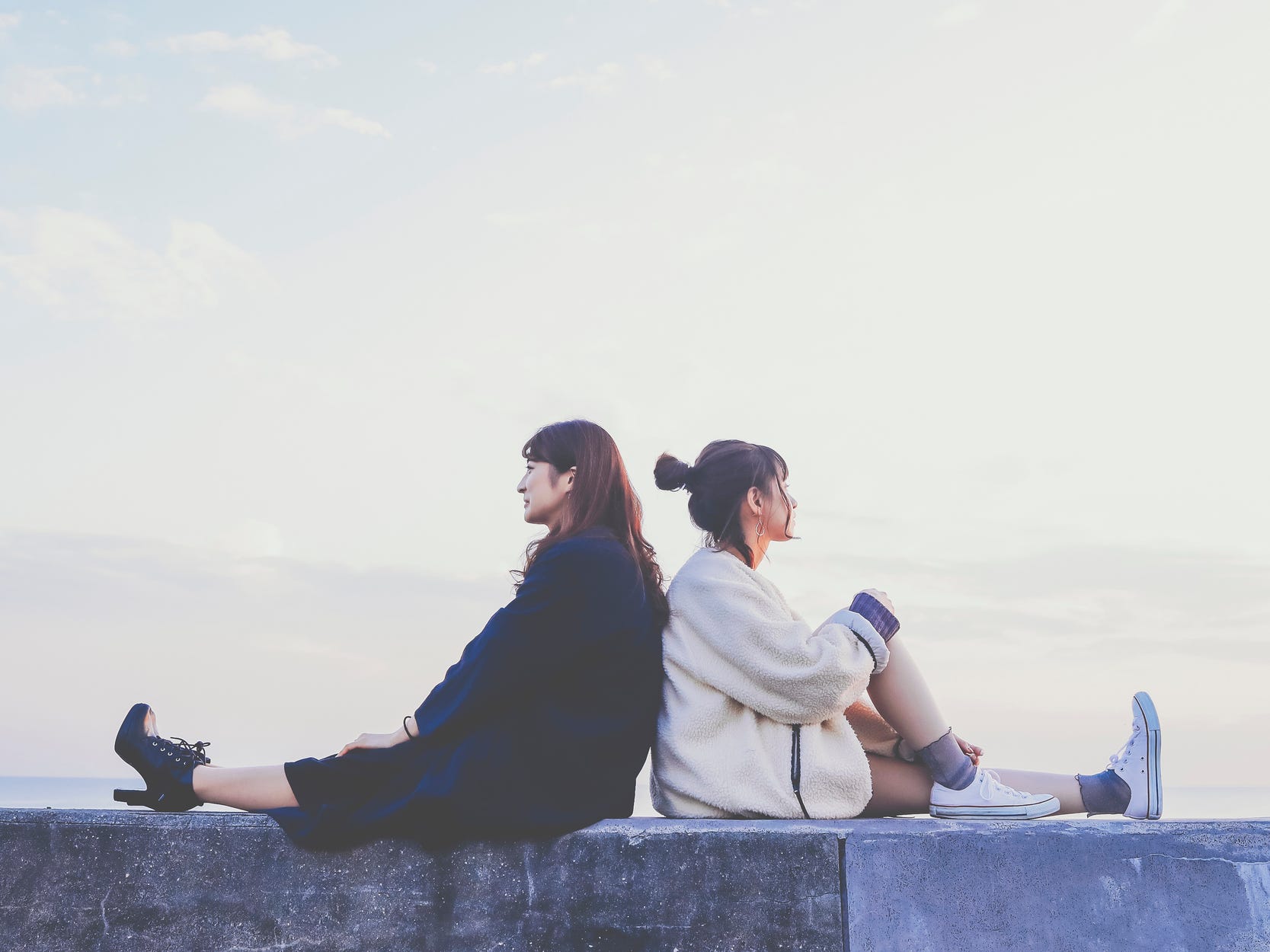 Two women sitting back to back