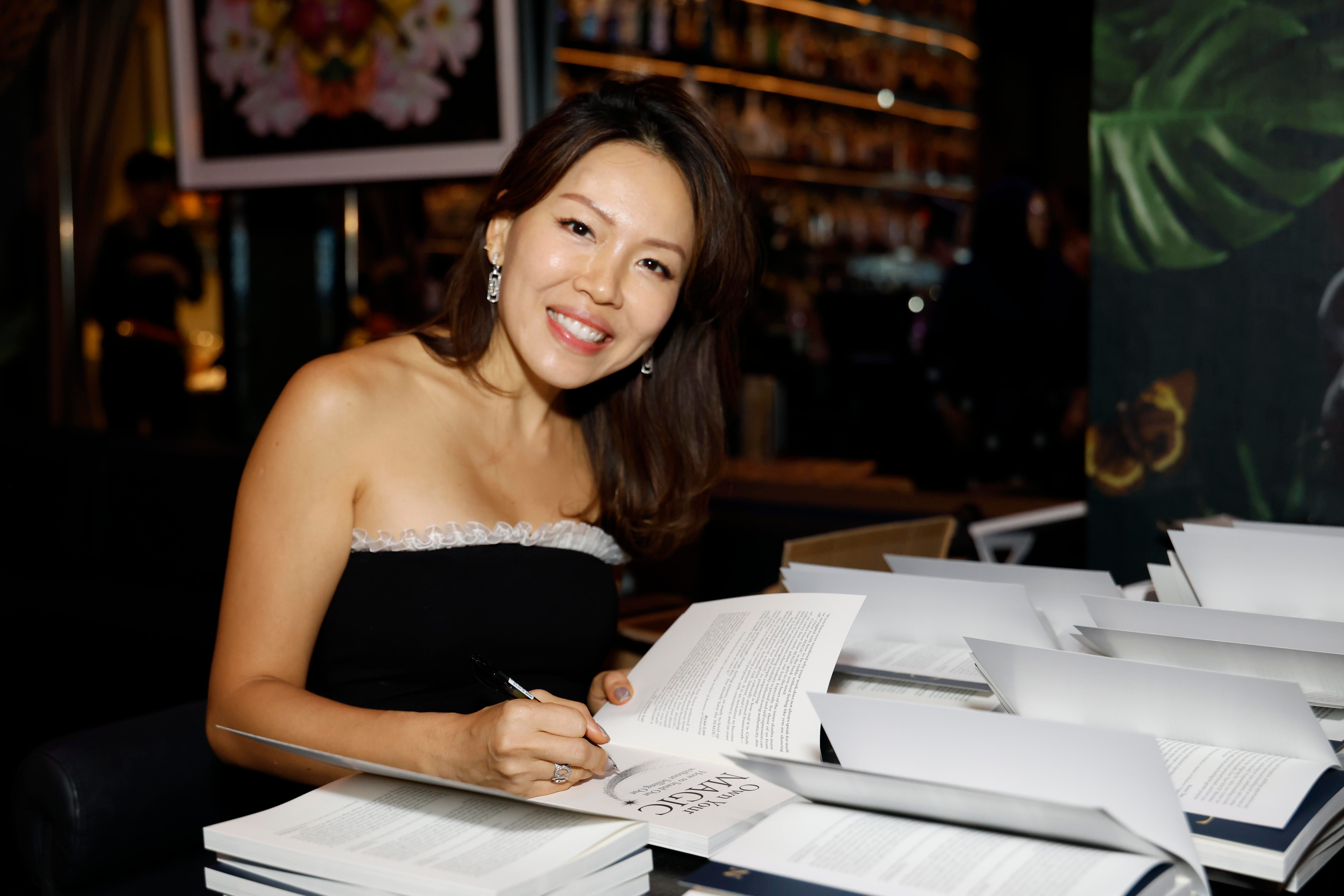 Cindy Tan signing books at a table.