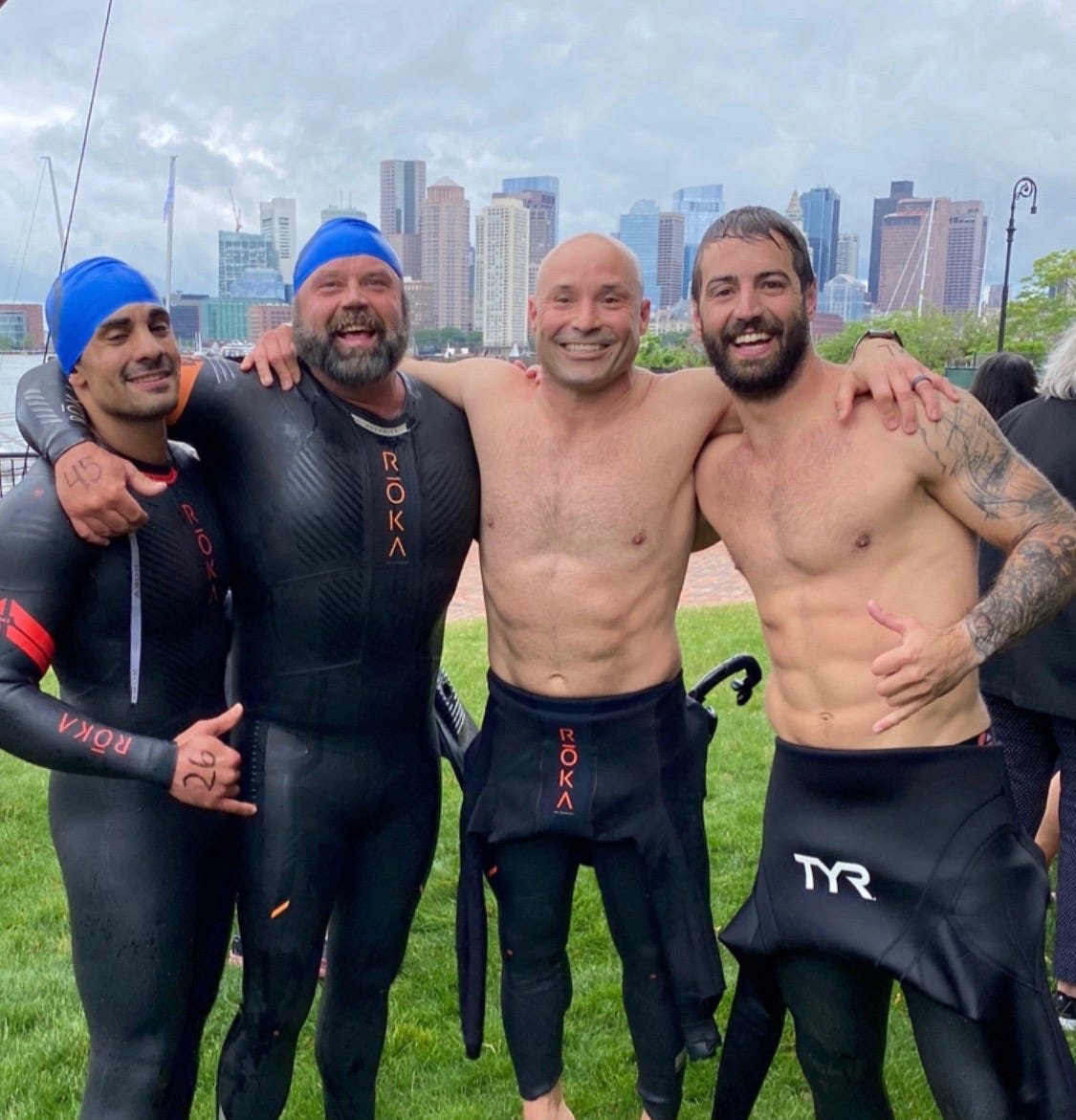 Navy veteran Brian Valenza with friends in a wetsuit after an open water swim in NYC.