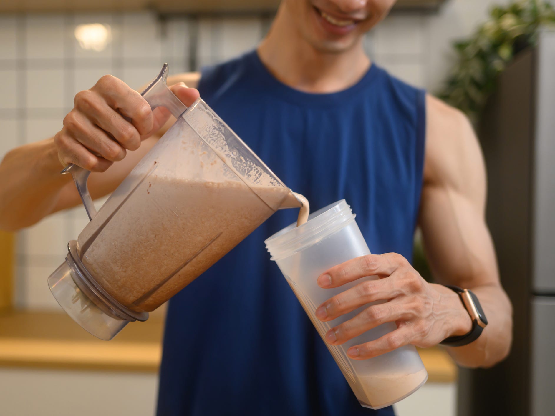 A man pouring a protein shake from a blender