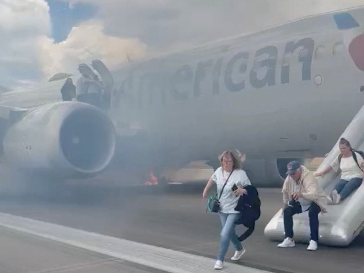 Passengers evacuate an American Airlines plane by an emergency slide as a fire burns and smoke emits from the aircraft, at the Denver International Airport, Denver, Colorado, U.S. July 26, 2025,