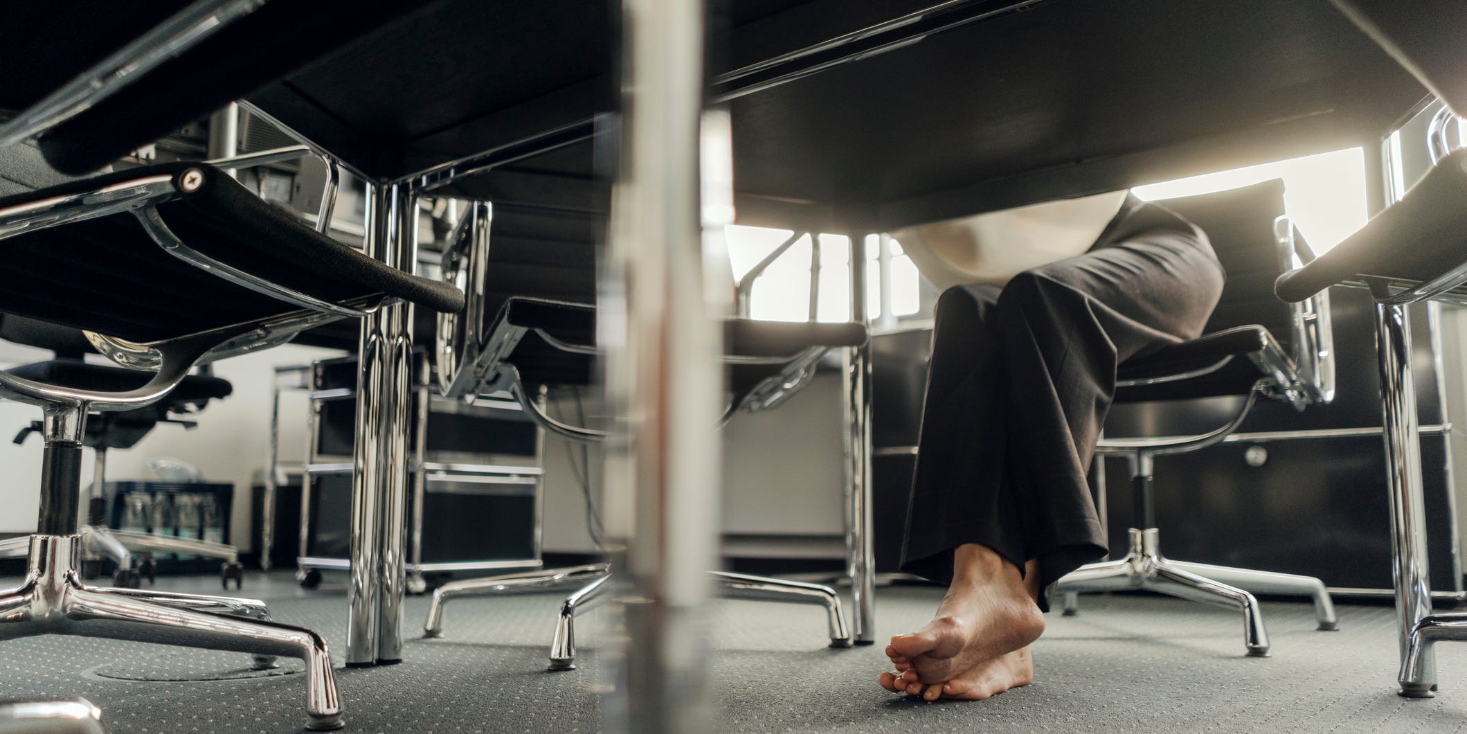 A person sits at a desk with no shoes.