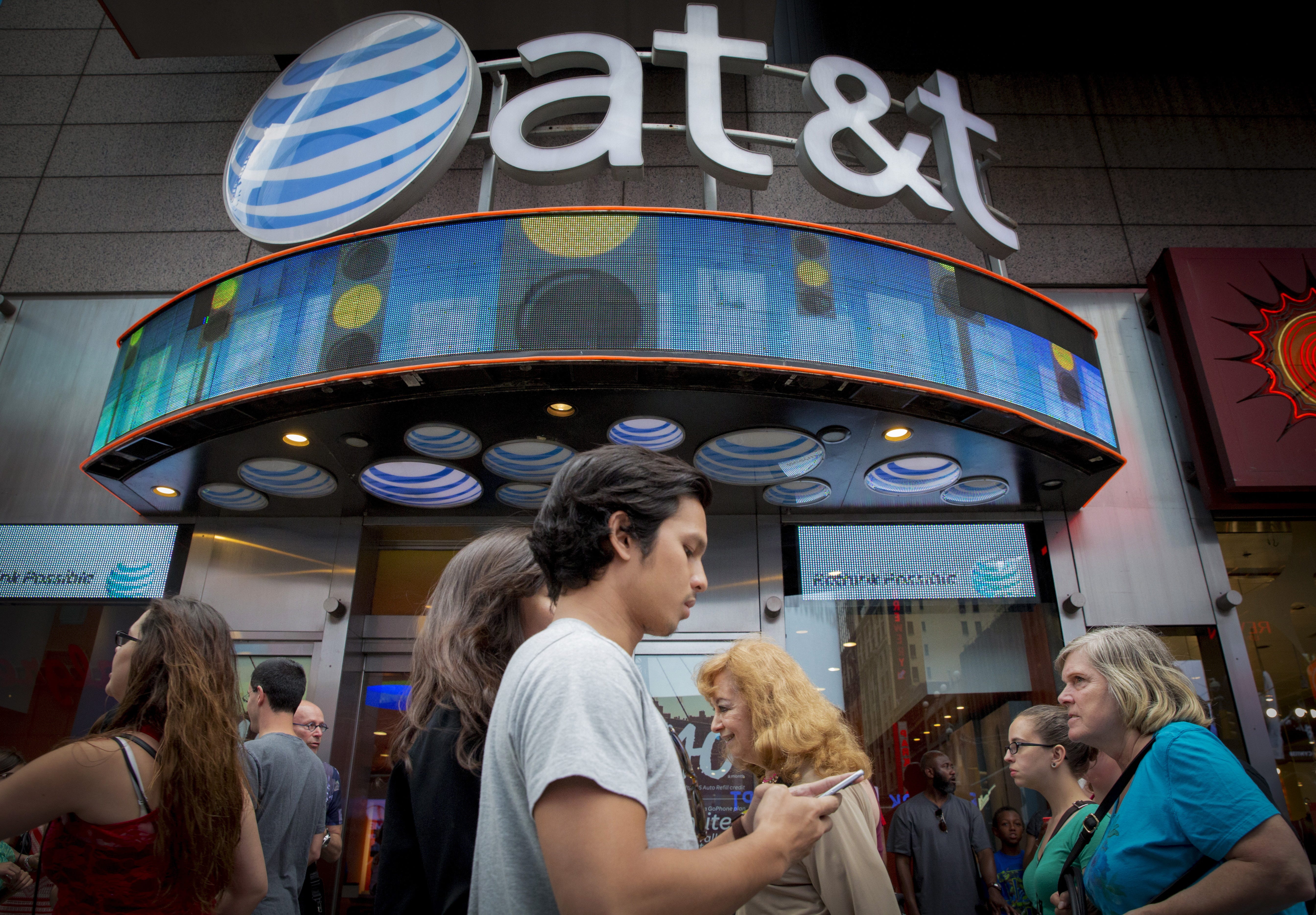 People walk past an AT&T store