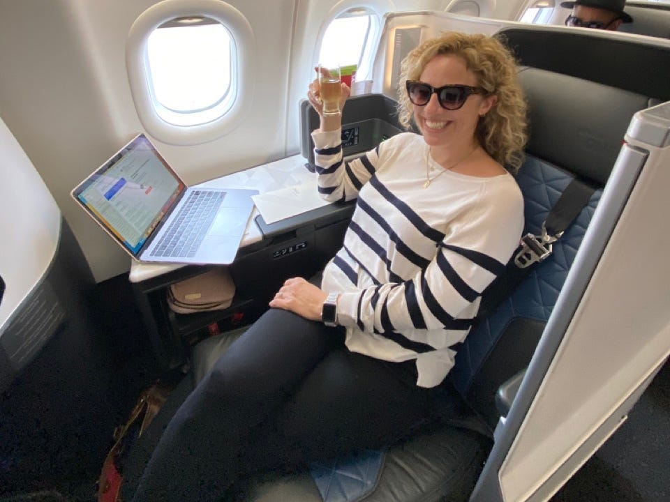 Author Alesandra Dubin smiling with drink in Delta One seat