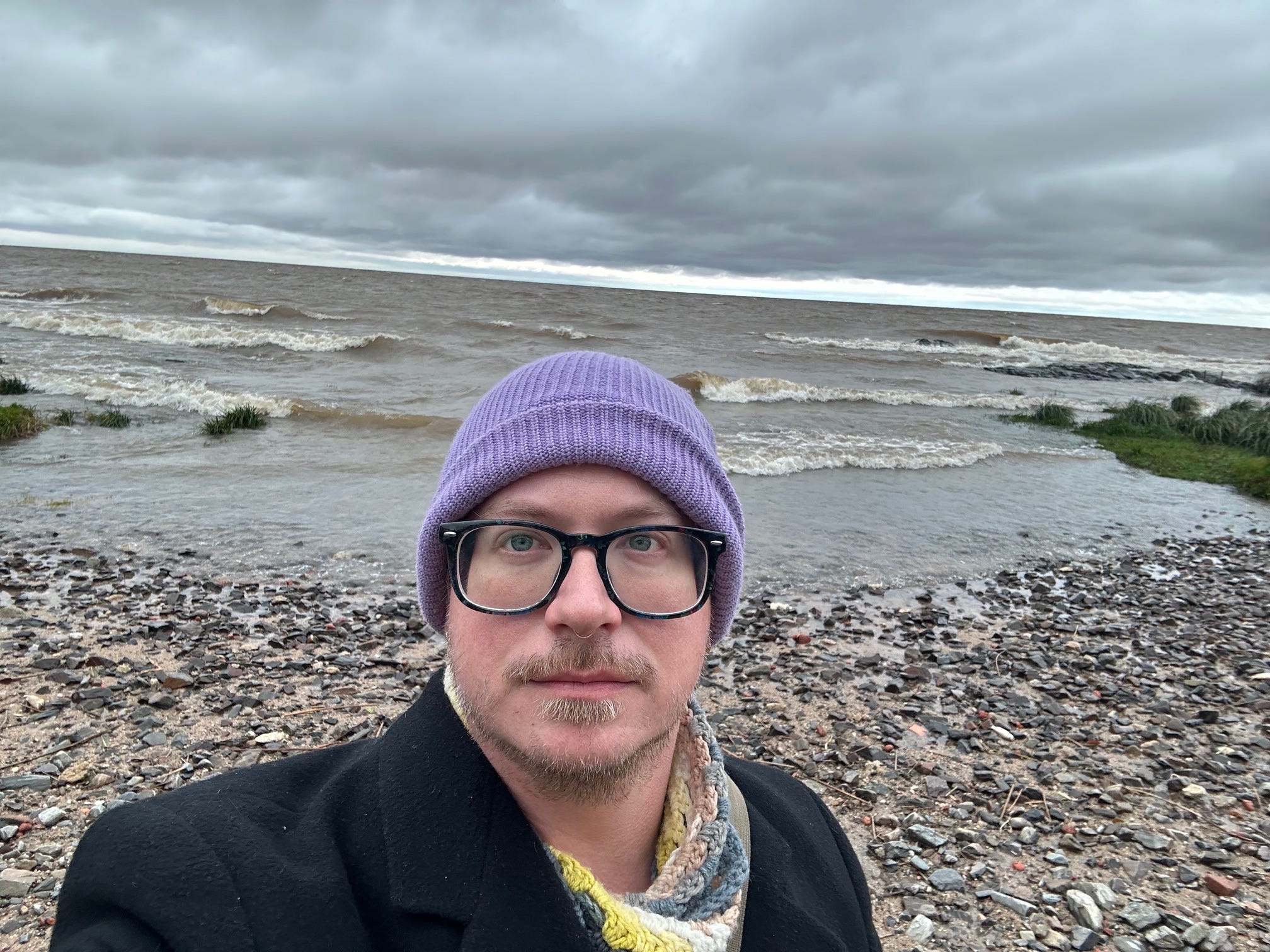 The author wearing a purple hat and standing on a beach.