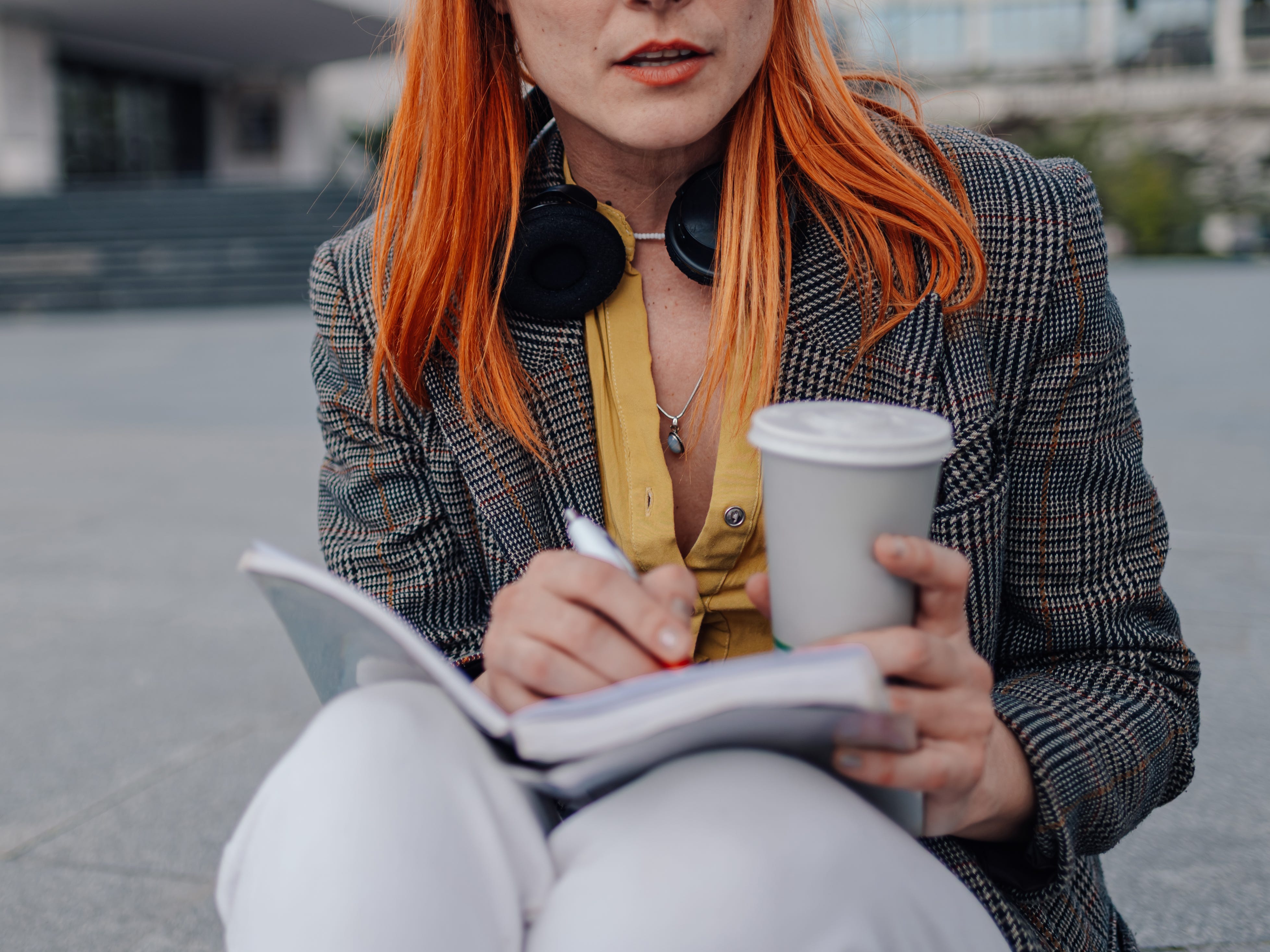 a woman holding a pen,  notebook, and coffee cup
