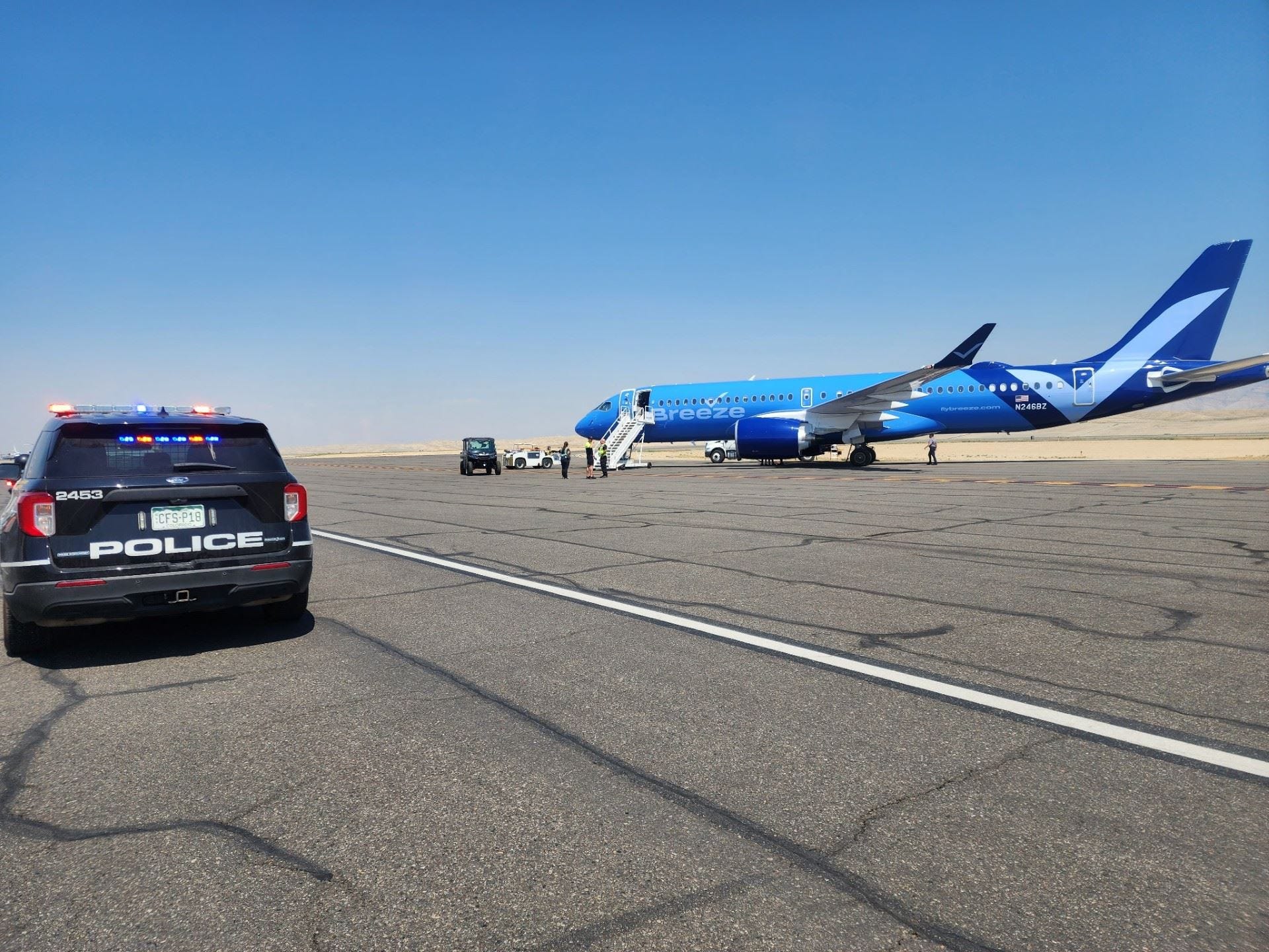 A police car and a Breeze Airways Airbus A220 parked on the tarmac at Grand Junction Airport in Colorado