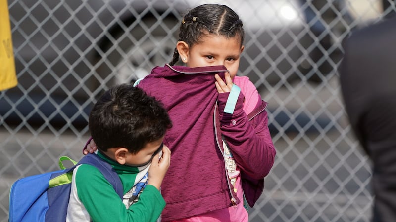 CUDAHY, CA - JANUARY 14: Children covering their noses and mouths leave school where 26 people, 17 children and 9 adults, were treated for jet fuel exposure at Park Avenue Elementary School in Cudahy on Tuesday, Jan. 14, 2020. A jet returning to LAX dumped its fuel over the neighborhood and the school. Affected people at the school were treated for skin and eye irritation. No patients were transported to hospitals.