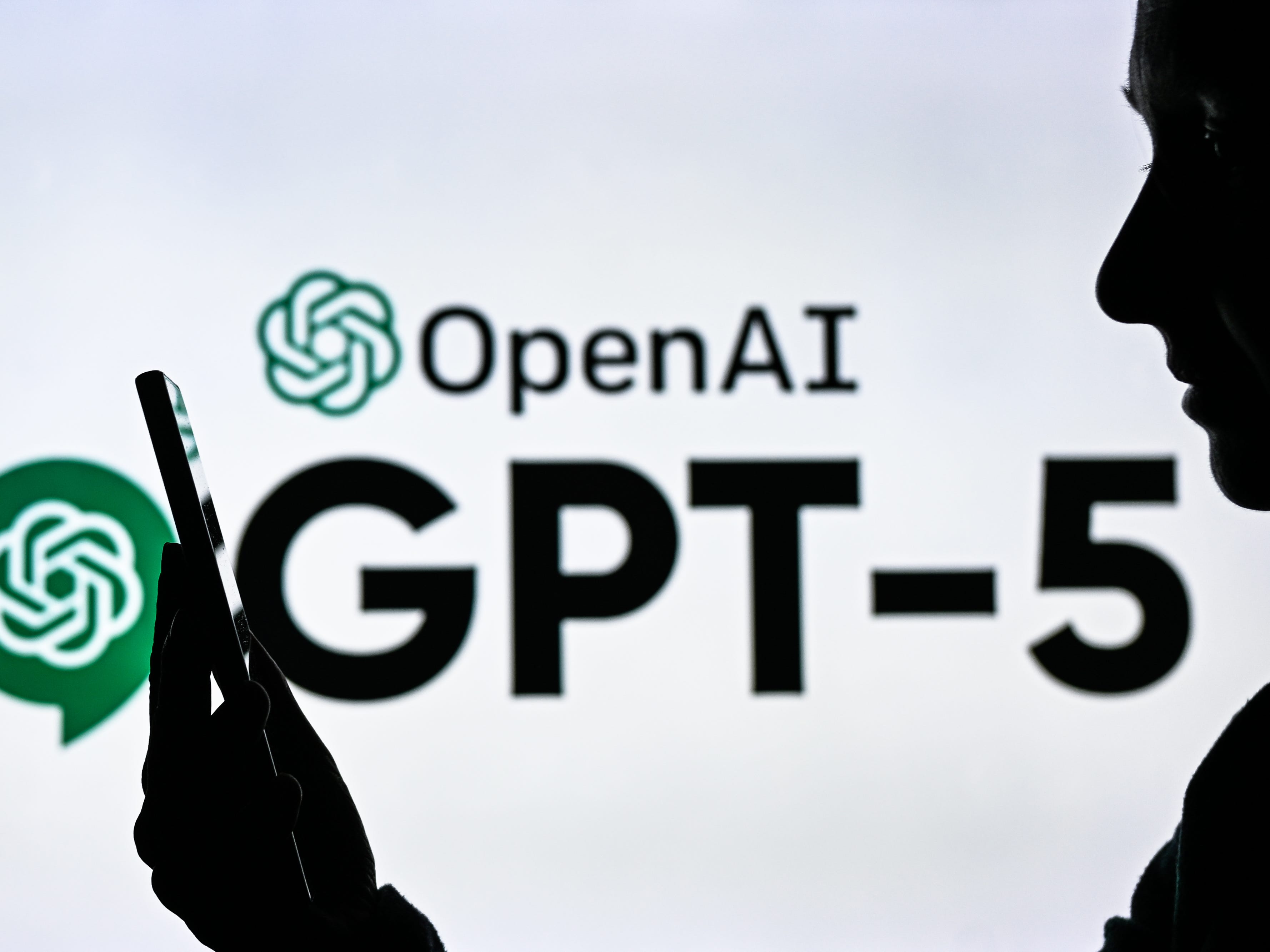 OpenAI logo with text that says GPT-5 behind a person holding a phone
