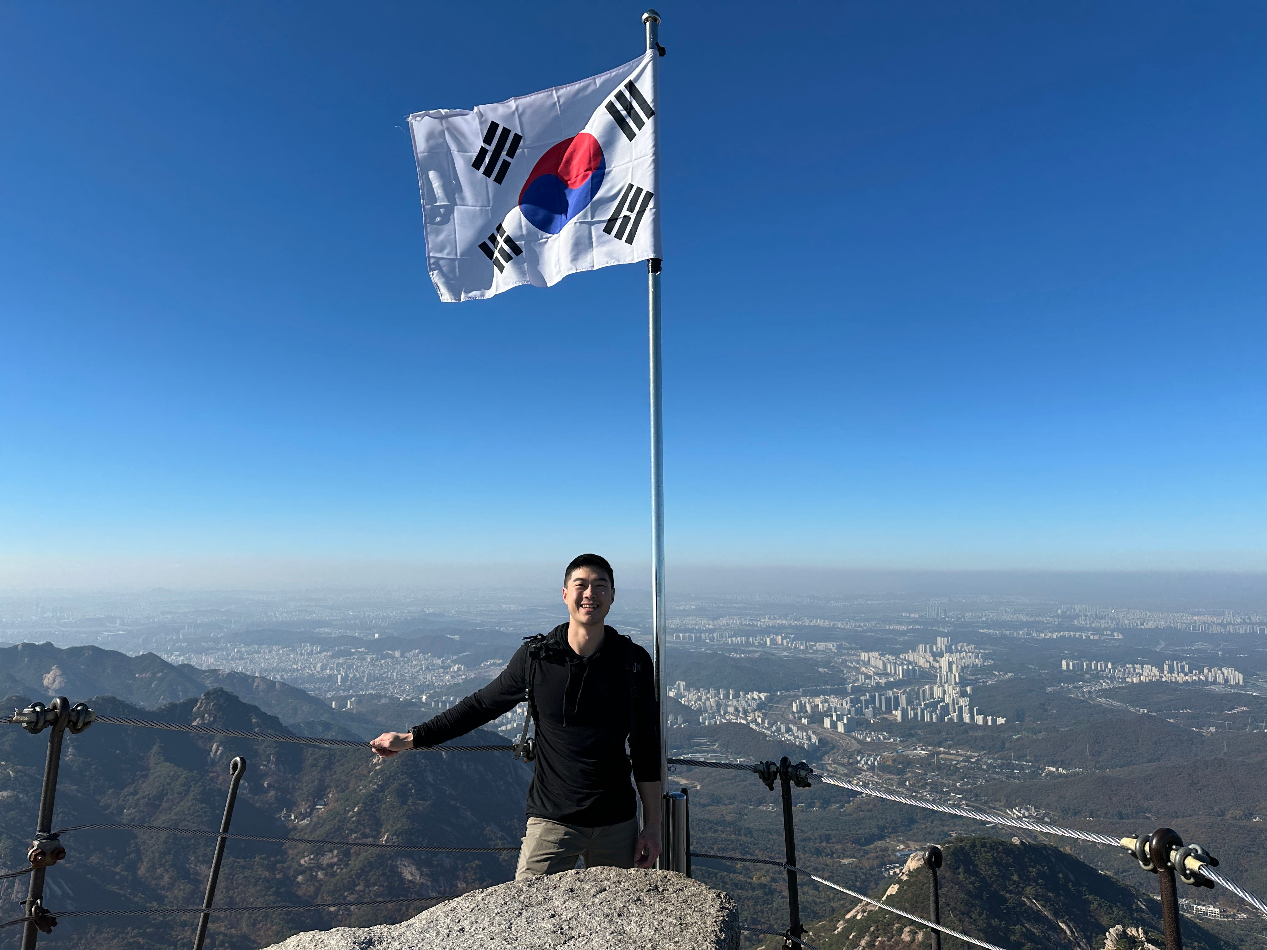 Tyger Cho standing by the South Korean flag in Bukhansan National Park.