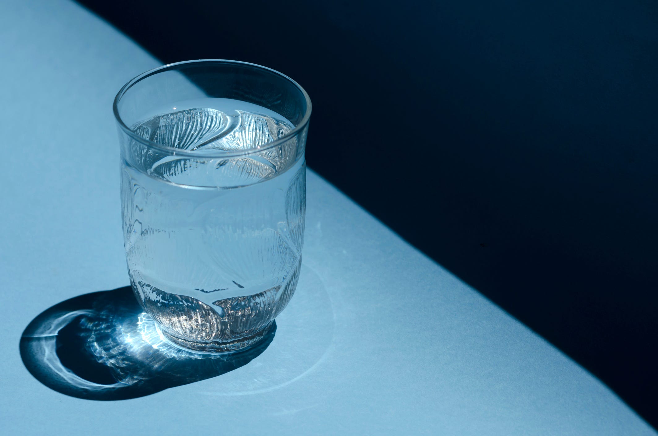 a close up of a glass of water on a blue background.