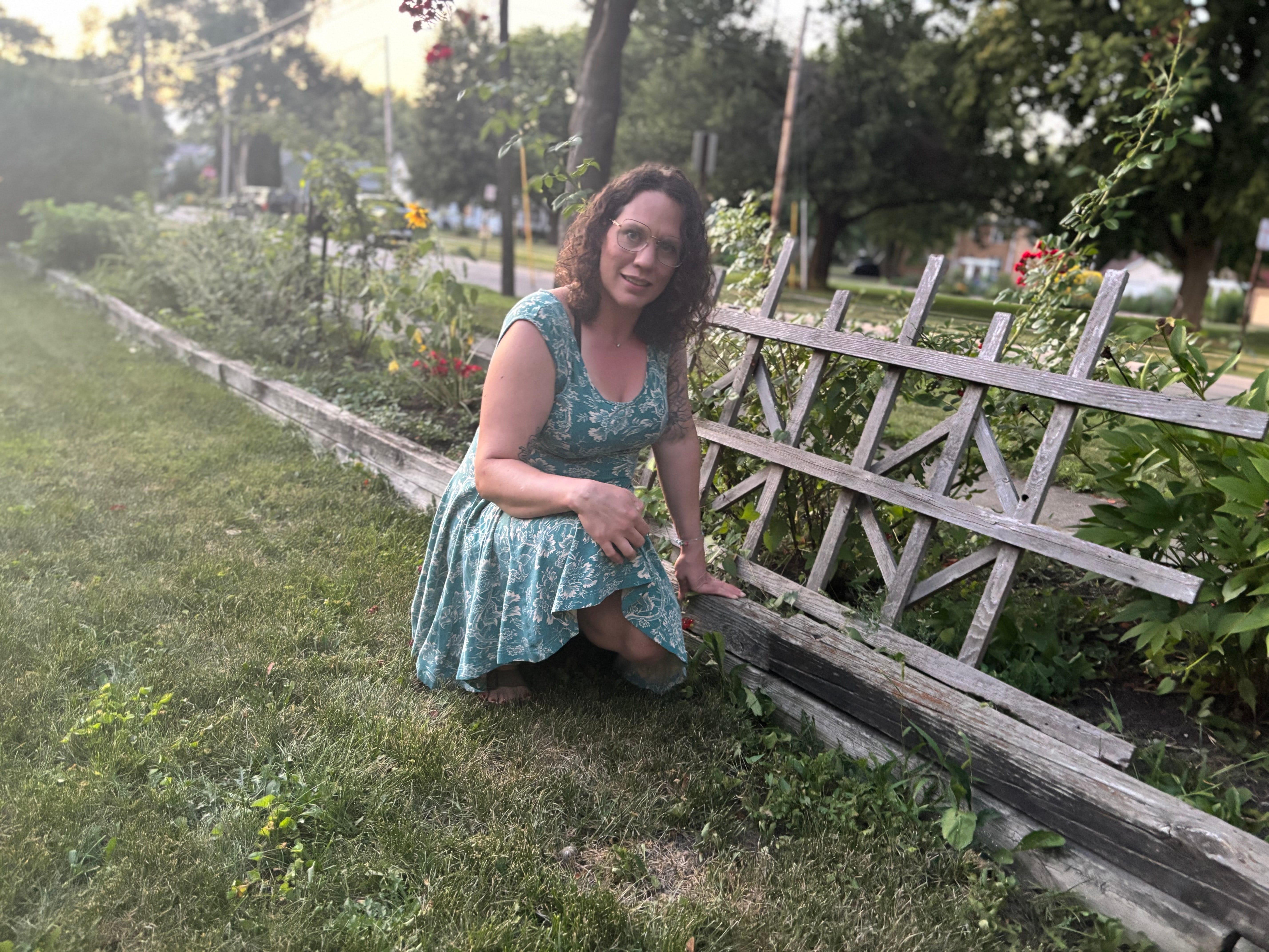 woman in green dress standing next to a garden