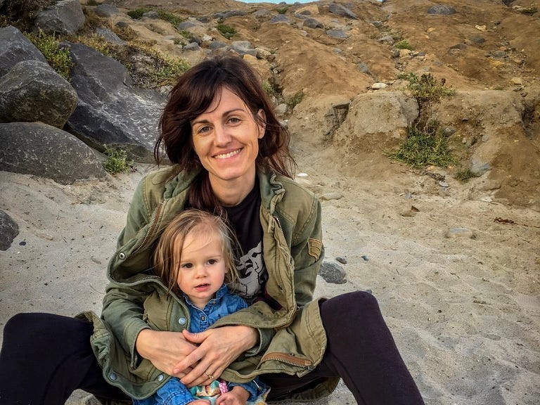 The author sitting on a beach with her child.