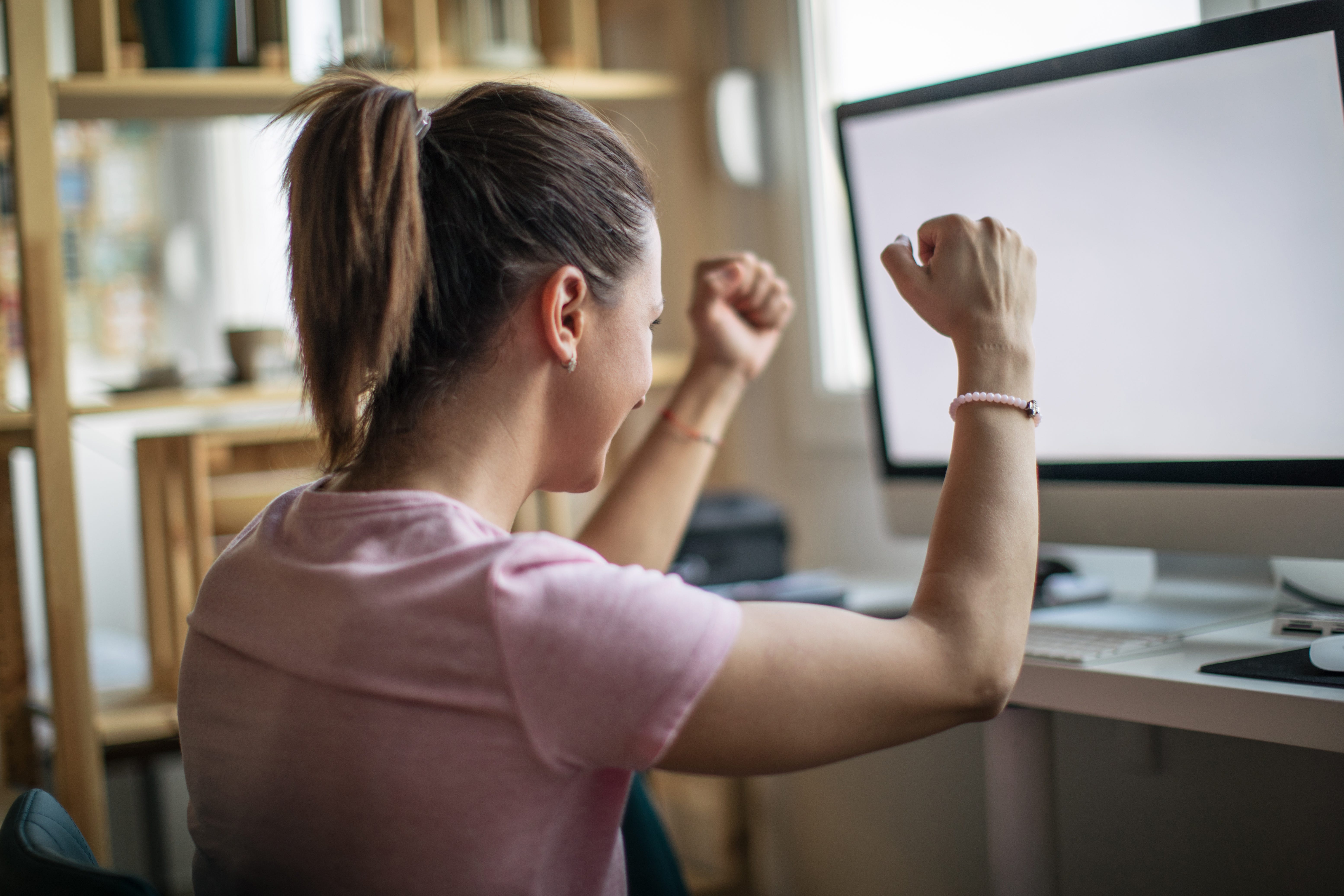 A woman celebrates a win in front of her computer