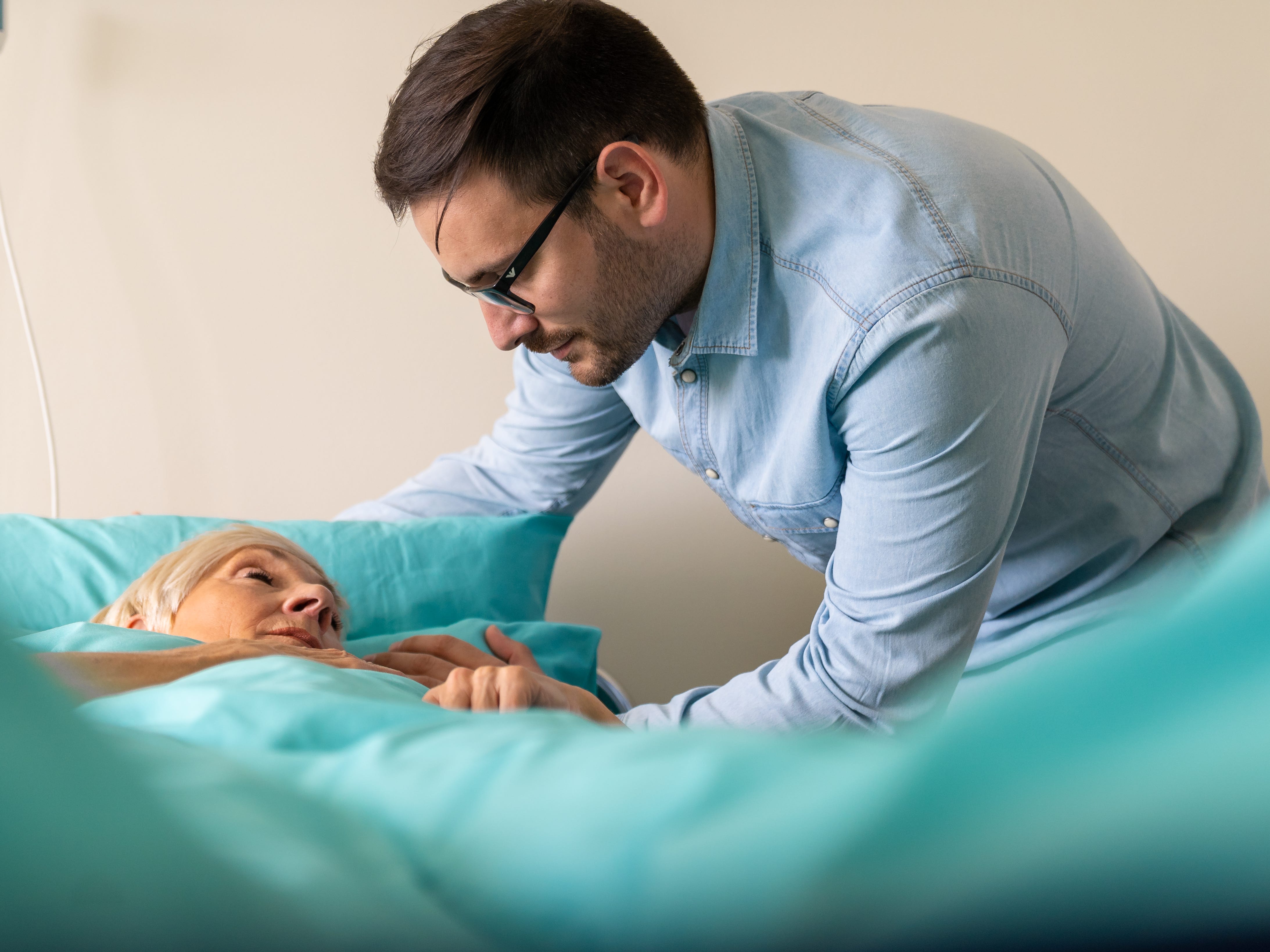 a man holding the hand of his dying mother
