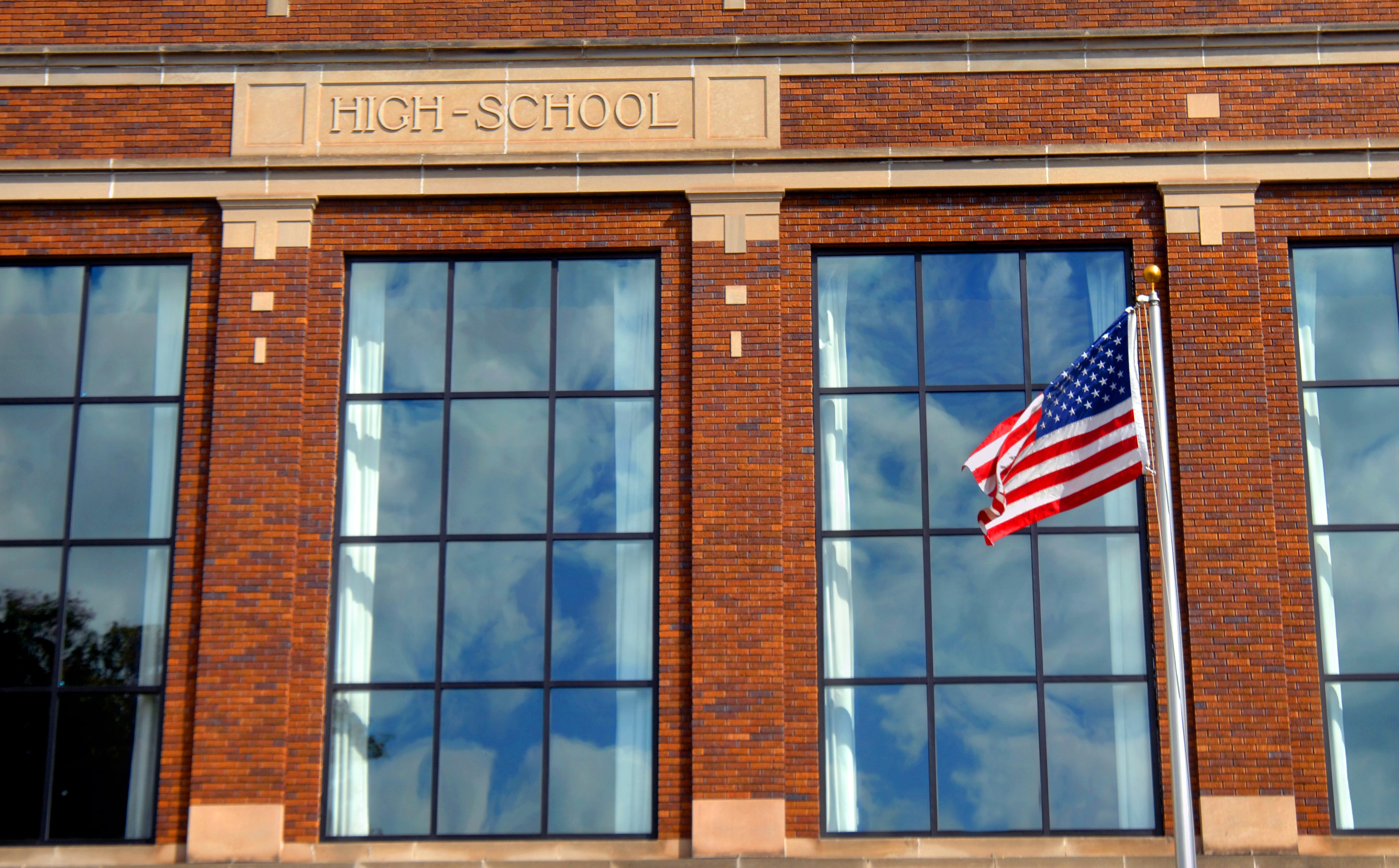 A high school façade with an American flag in front.