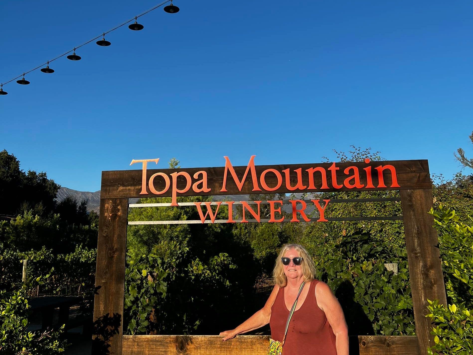 woman stand in front of topa mountain winery welcome sign