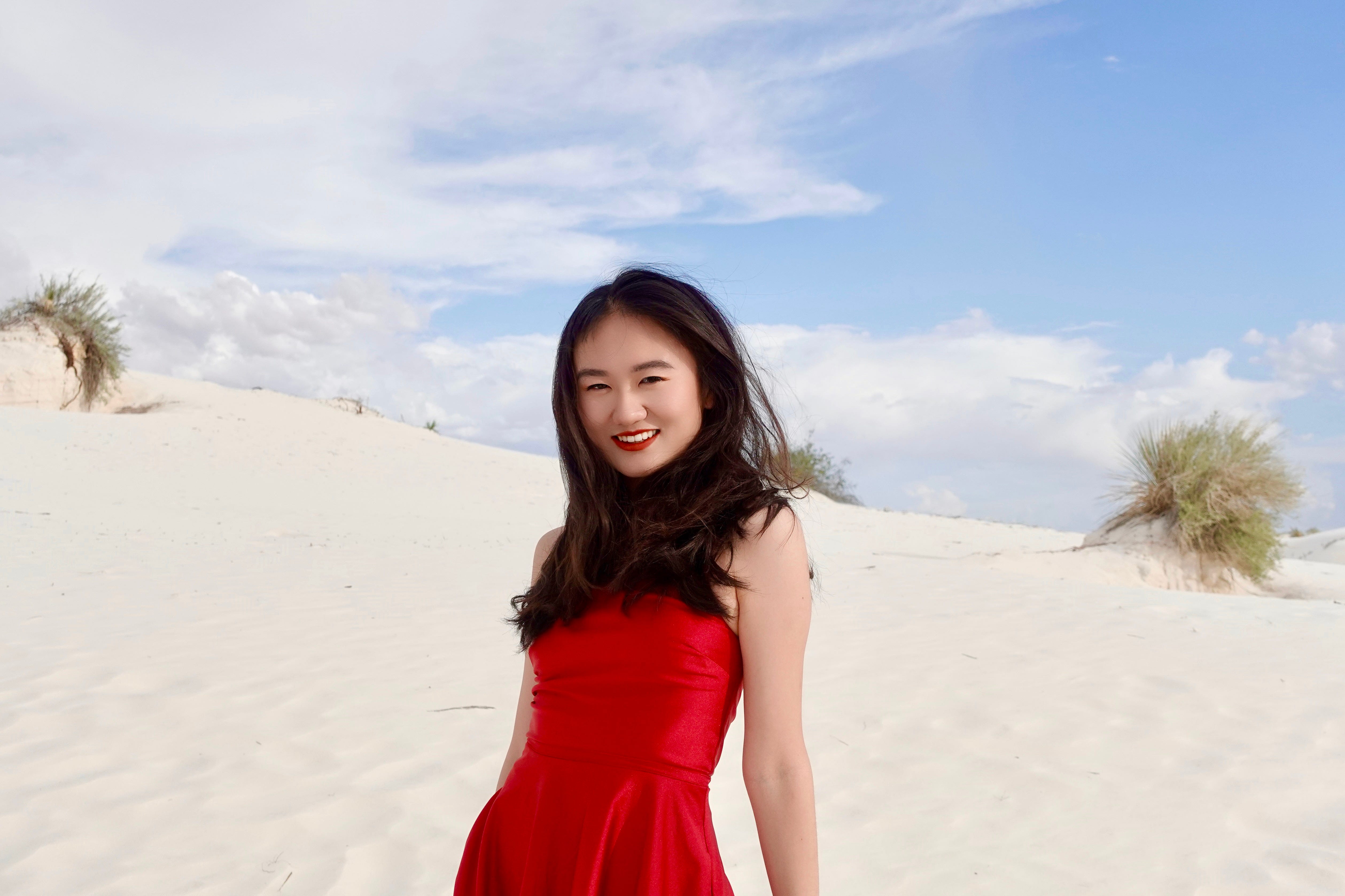 Woman standing in a desert wearing a red dress.