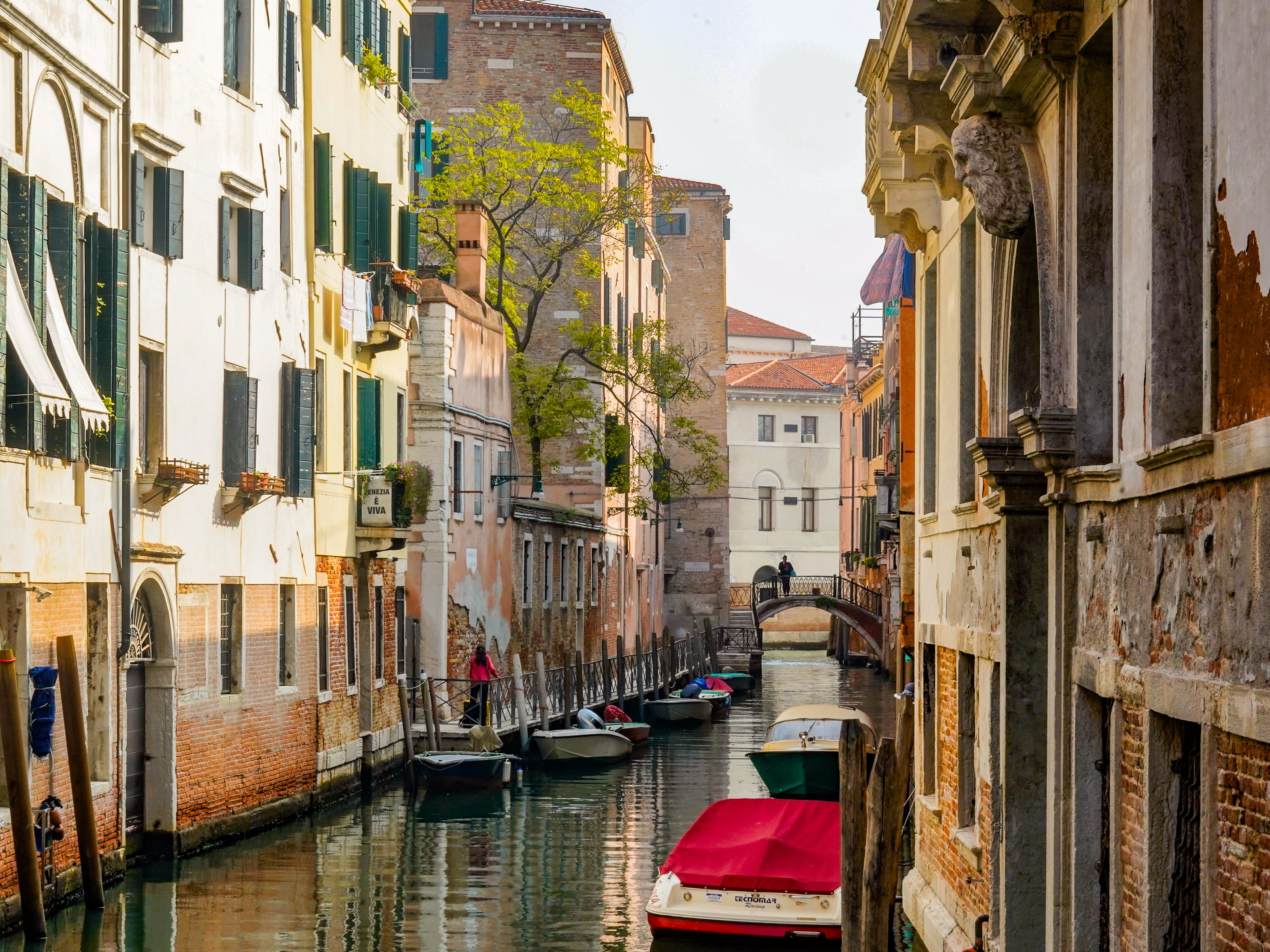 Boats parked in a canal between rows of buildings in Venice, Italy